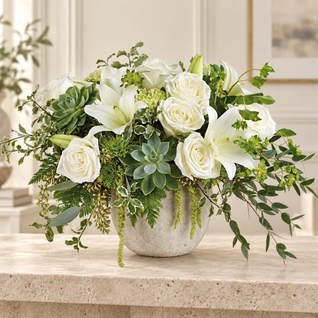 White roses and lilies arranged in a gray vase with green succulents