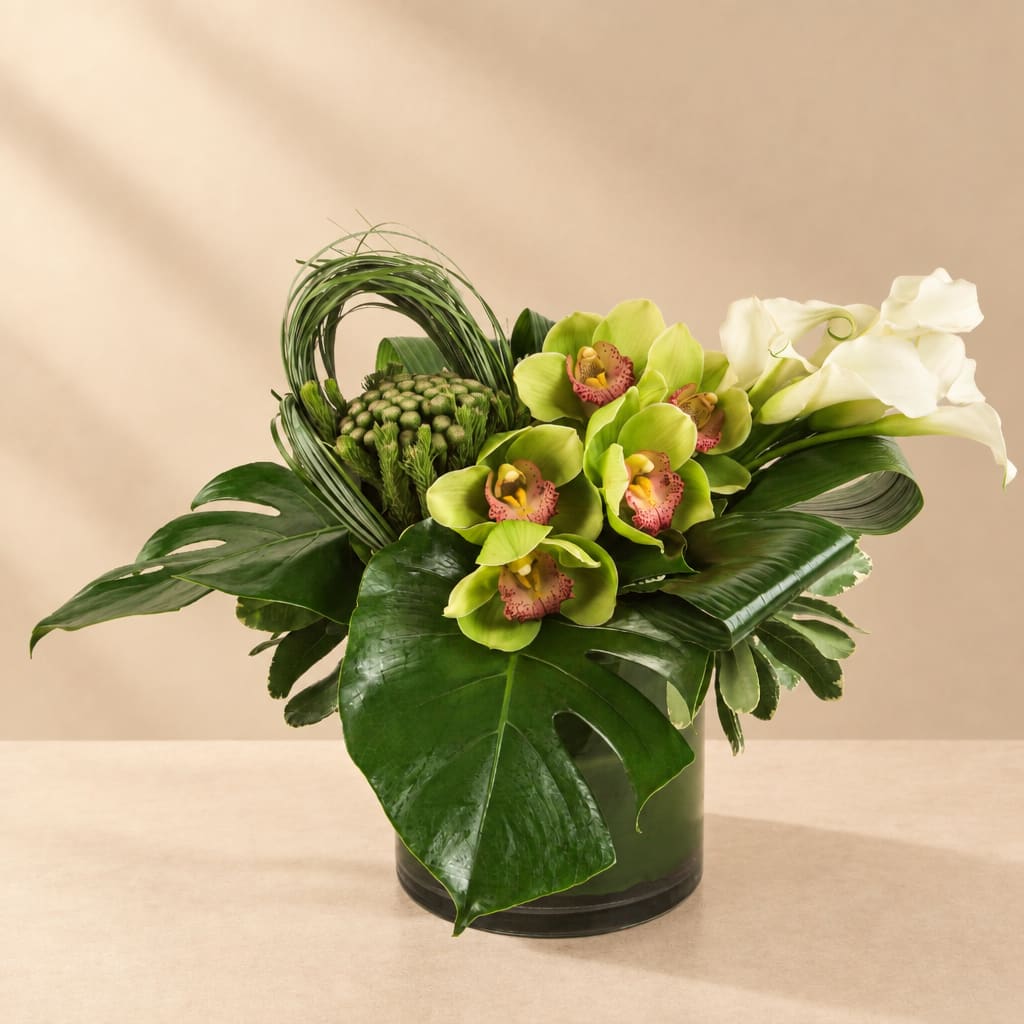 Green orchid and calla lily arrangement in a dark vase