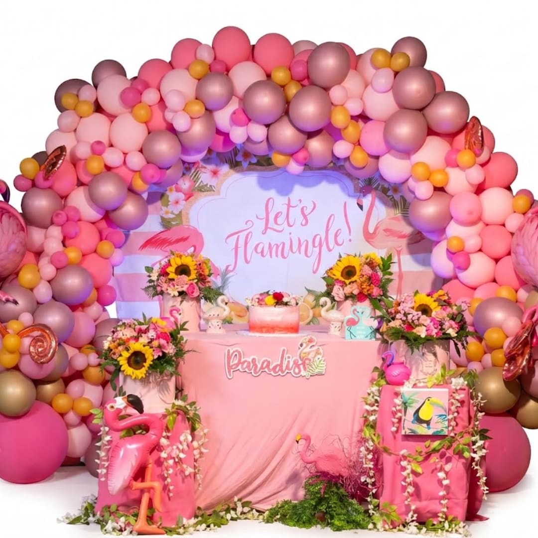 Pink balloon arch around floral party display with flamingo decor