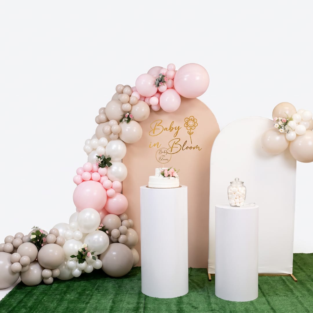 Pastel balloon arch with small floral accents around a baby shower backdrop