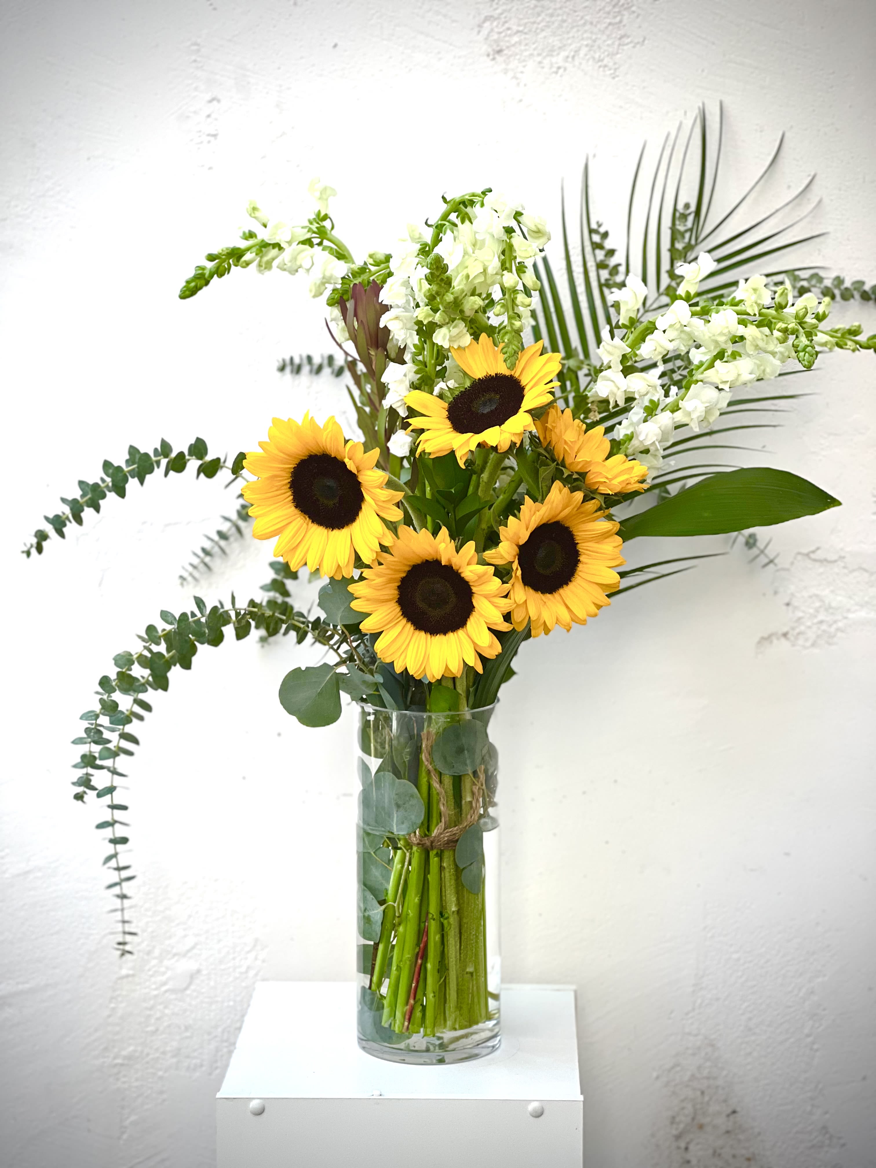 Sunflowers in a clear glass vase with white snapdragons