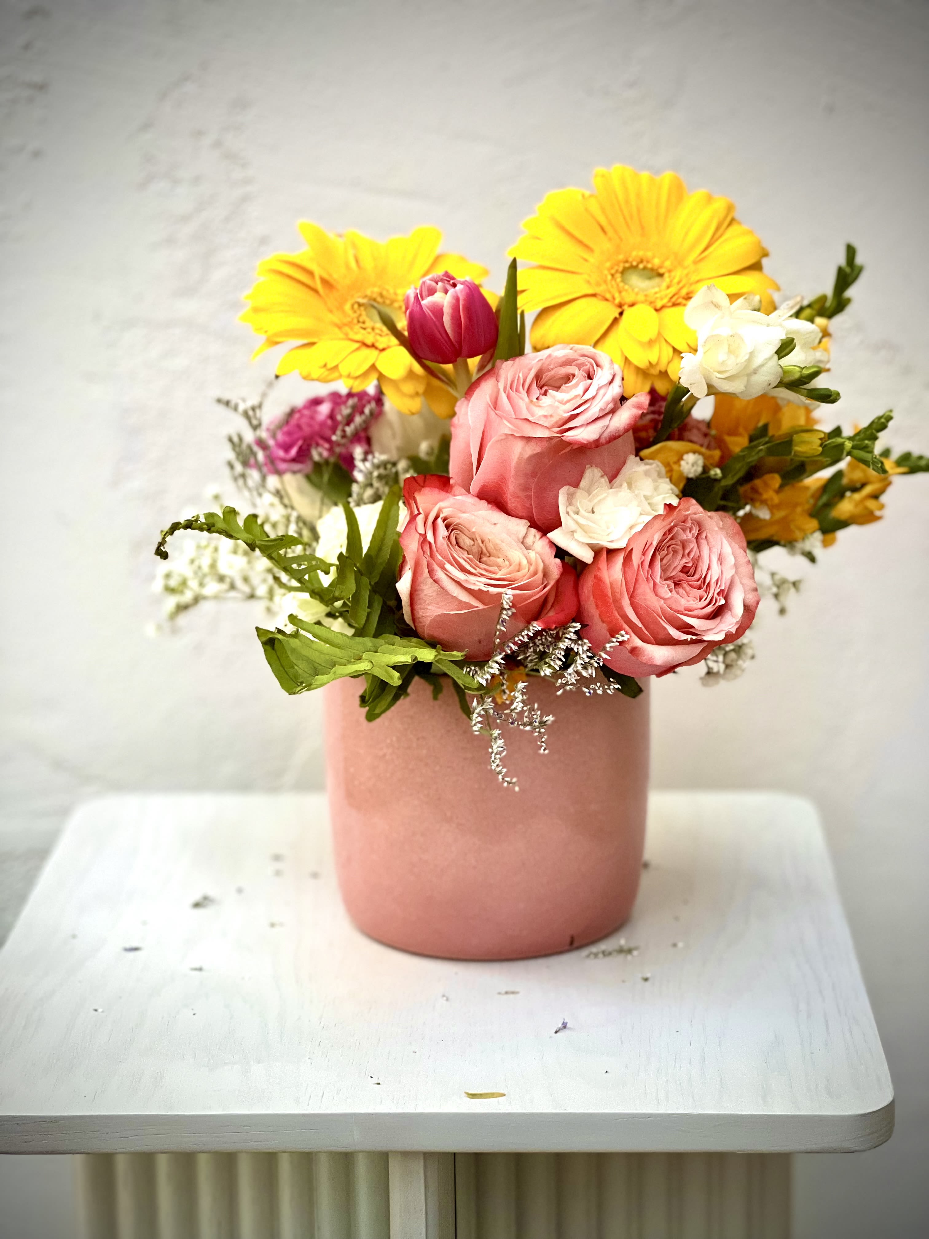 Pink roses and yellow gerbera daisies in a blush vase