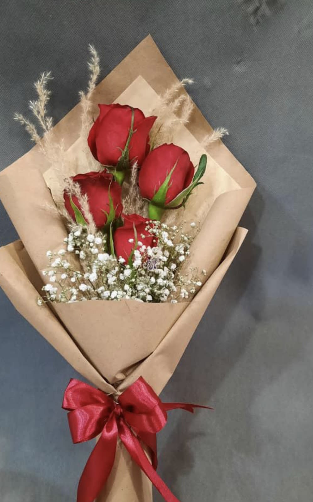 Bouquet of red roses wrapped in brown paper with a red ribbon