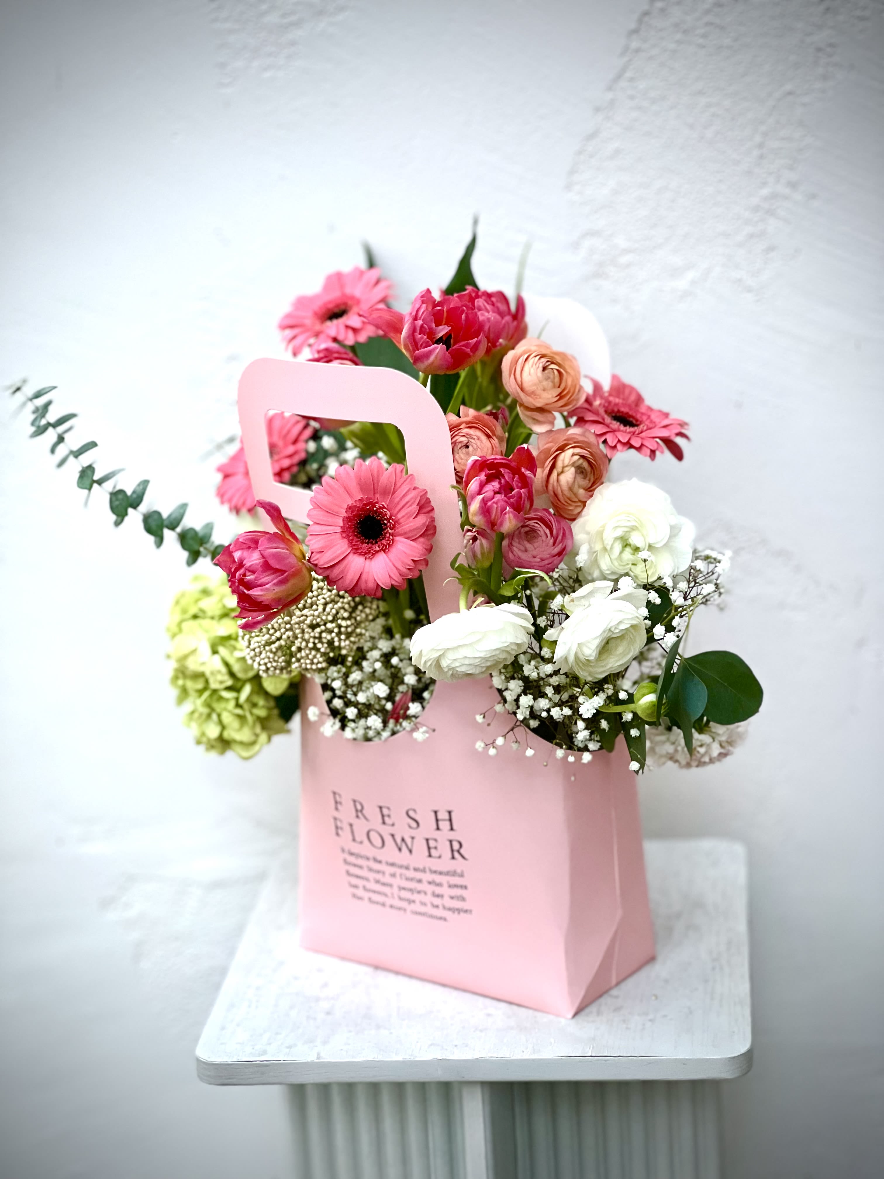 Pink and white mixed flower arrangement in a pink gift bag