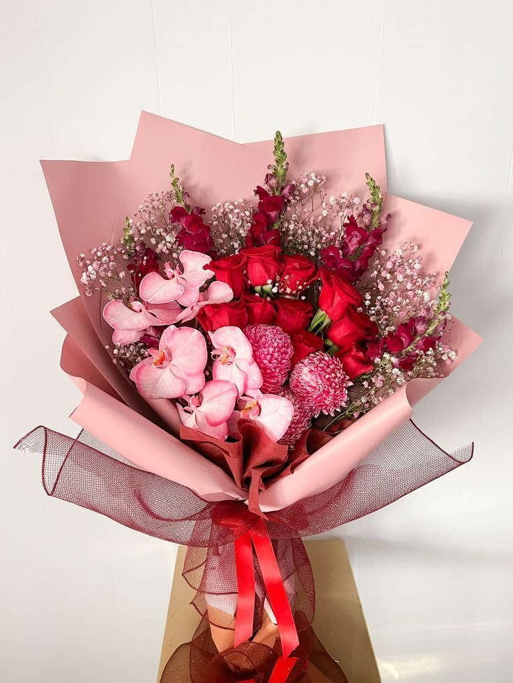 Bouquet of red roses and pink orchids wrapped in pink paper