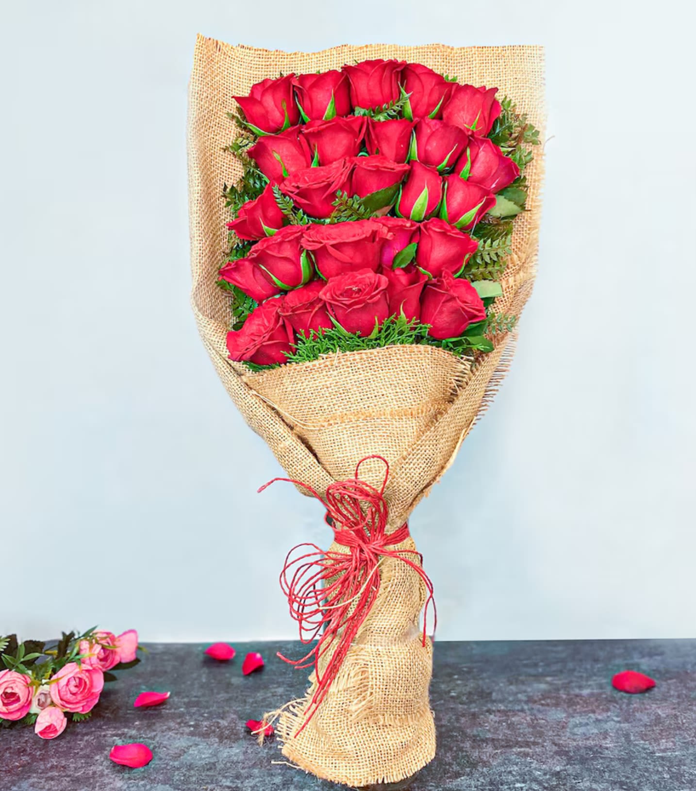 Bouquet of red roses wrapped in burlap with a red tie