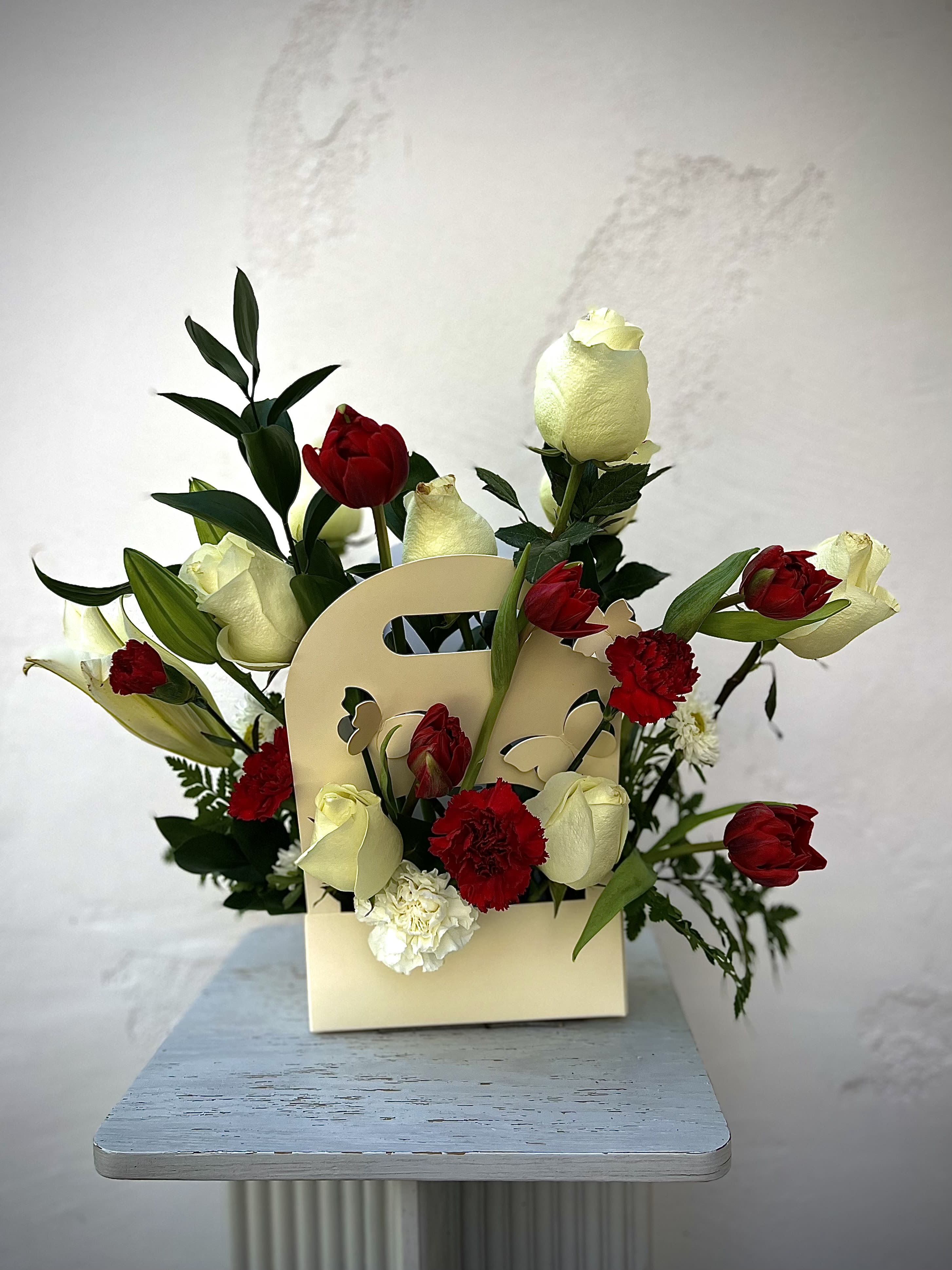Red and white tulips with carnations in a cream gift bag