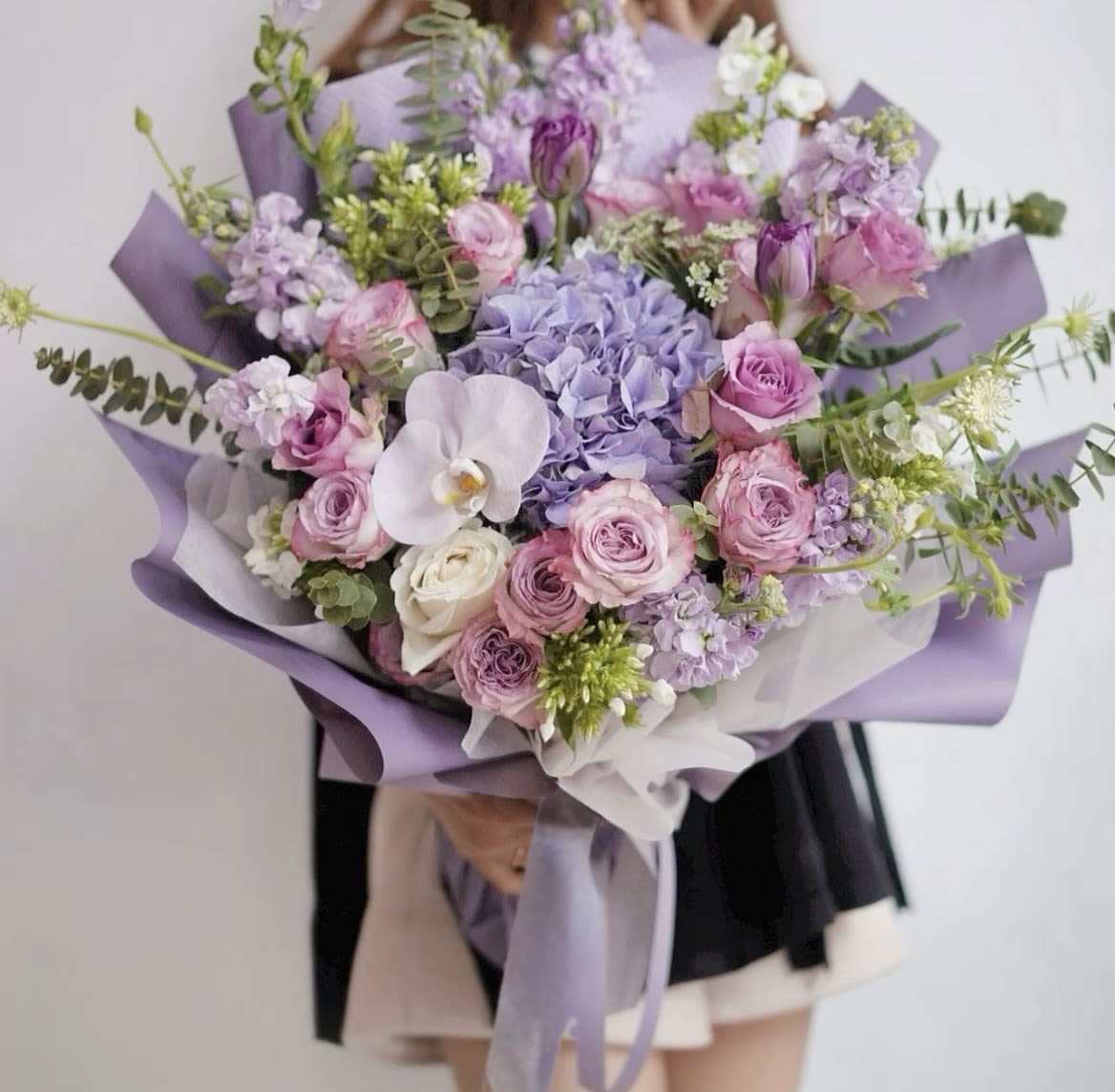 Large bouquet of pink and lavender flowers wrapped in purple paper