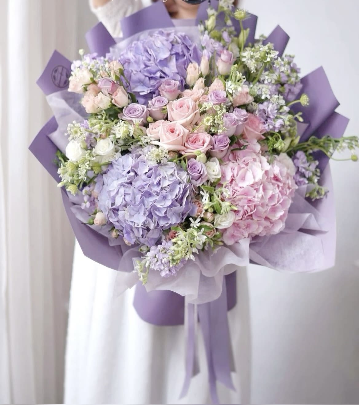 Lavender and pink bouquet with roses and hydrangeas wrapped in purple paper