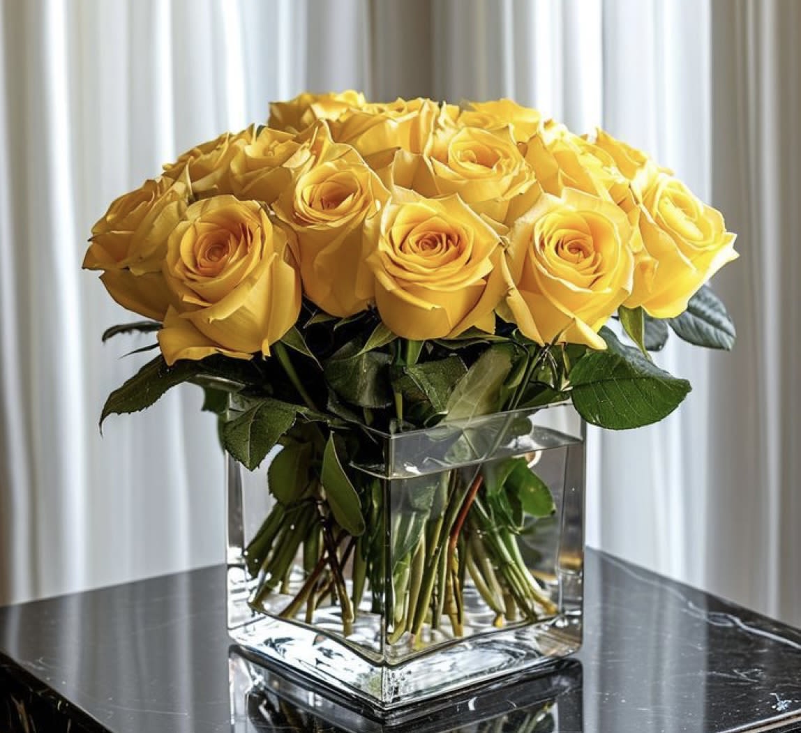 Yellow roses arranged in a clear square glass vase