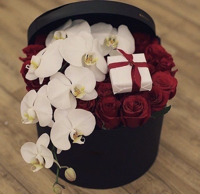 Black hatbox with white orchids, red roses, and a small gift box