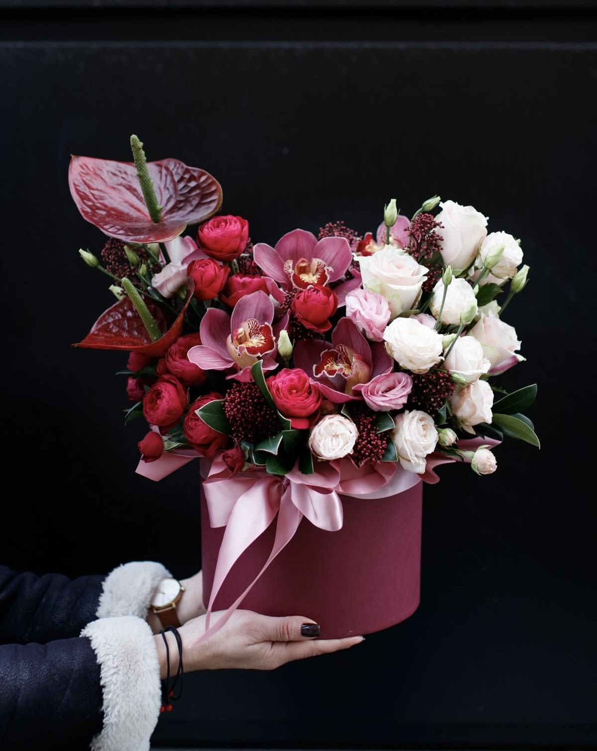Pink and white floral arrangement in a round box with ribbon