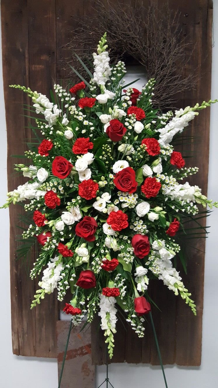     Eternal Peace Tribute - Honor life’s most meaningful moments with our elegant Red &amp; White Sympathy Standing Spray. Thoughtfully designed with premium red roses, white roses, carnations, and delicate seasonal blooms, this arrangement expresses love, respect, and remembrance in the most graceful way.  The striking contrast of deep red and pure white symbolizes both enduring love and peaceful rest, making it a perfect tribute for memorial services, funerals, or moments of condolence. Expertly arranged on a standing easel, this piece creates a powerful and dignified presence.  Each arrangement is handcrafted with fresh, high-quality flowers to ensure beauty, balance, and lasting impression during sensitive occasions.  Perfect for: • Funeral services • Memorial ceremonies • Sending condolences • Honoring a loved one