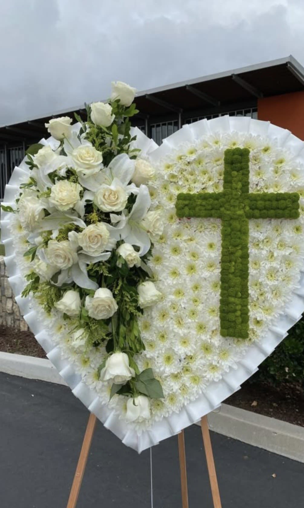Eternal Grace Cross Tribute - Honor your loved one with a timeless and elegant floral tribute. This handcrafted sympathy arrangement features delicate white roses and lilies, paired with a beautifully designed cross centerpiece—symbolizing peace, faith, and eternal remembrance.  Perfect for funeral services and memorials, this arrangement conveys heartfelt condolences with grace and dignity. Each piece is thoughtfully arranged to bring comfort during difficult times.  Order now to express your sympathy with a meaningful and respectful floral design.
