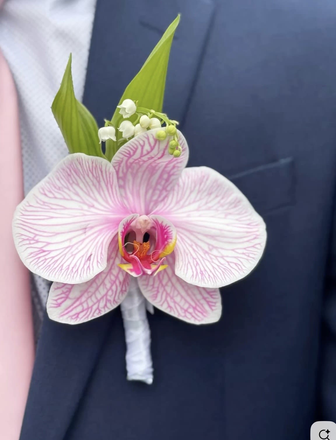 Royal Orchid Elegance _ Same Day Delivery  -  Add a touch of luxury and sophistication to your special day with our “Royal Orchid Elegance” boutonniere. Featuring a stunning white orchid with delicate pink veining and fresh green accents, this handcrafted floral piece is designed for modern gentlemen who appreciate timeless style.  Perfect for weddings, engagements, proms, and formal events. Elegant, unique, and unforgettable — a refined detail that completes your look beautifully.