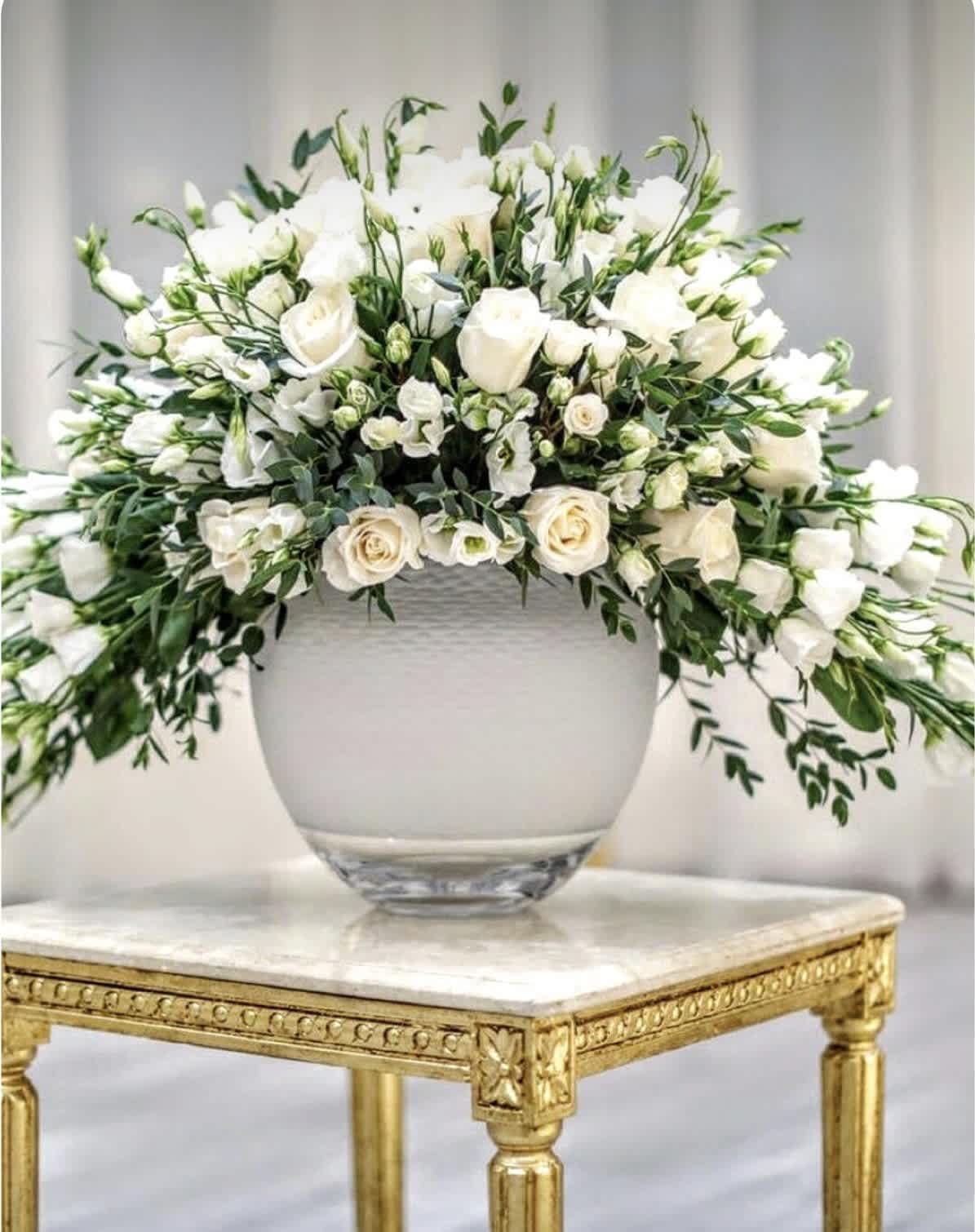 White floral arrangement in a glass vase on a gold table