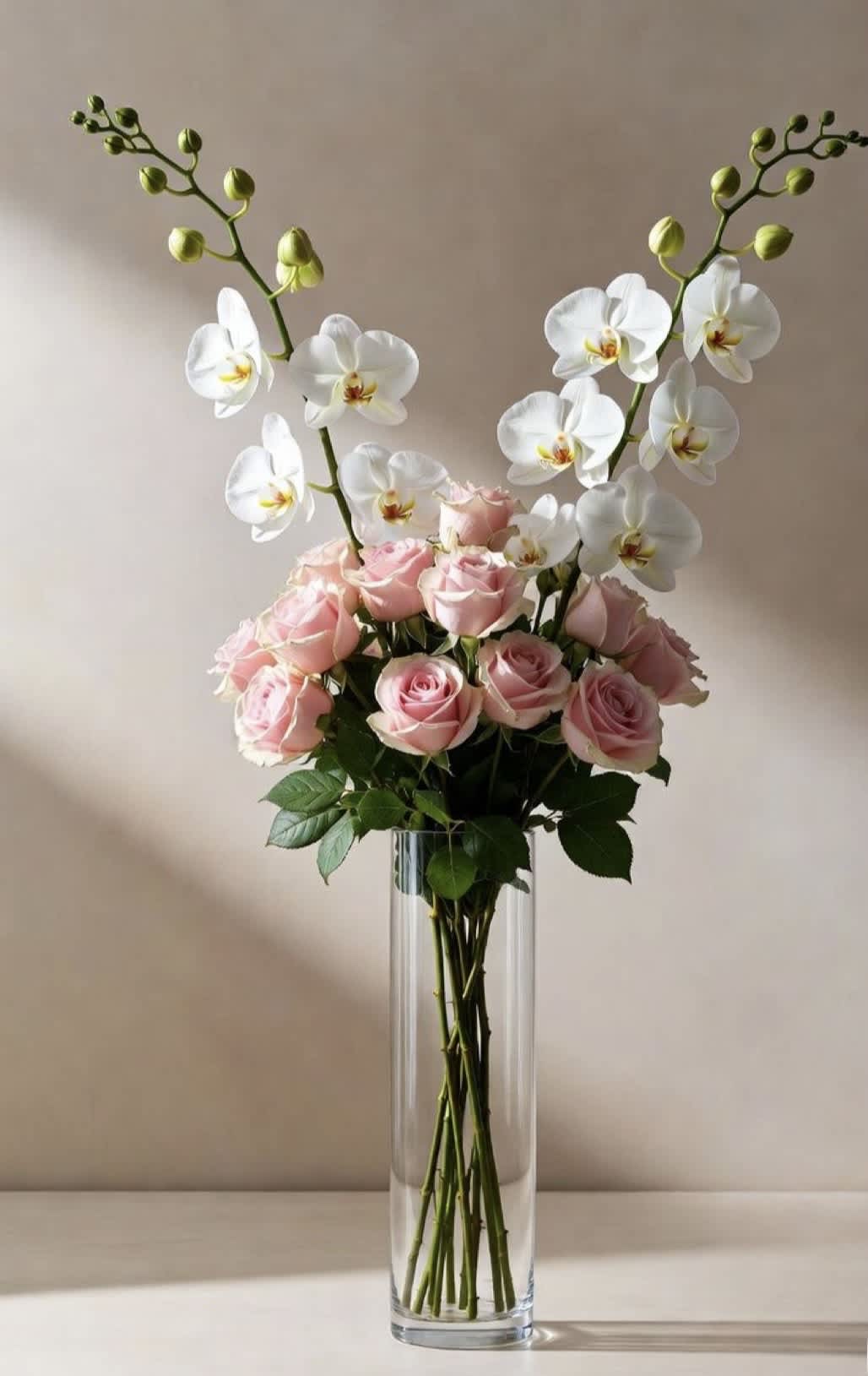 Pink roses and white orchids arranged in a clear glass vase.