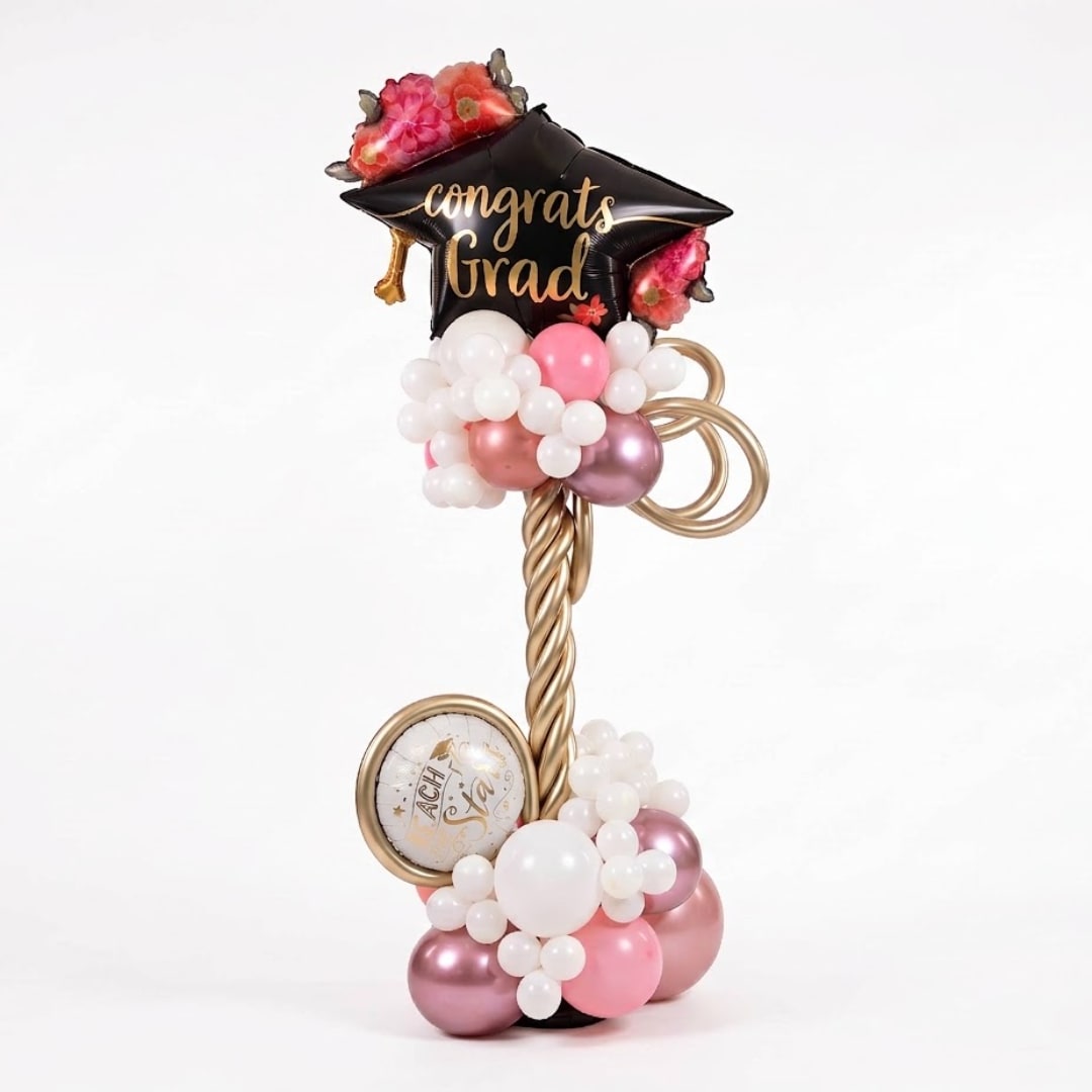 Graduation balloon display with a black cap balloon and pink and white balloons