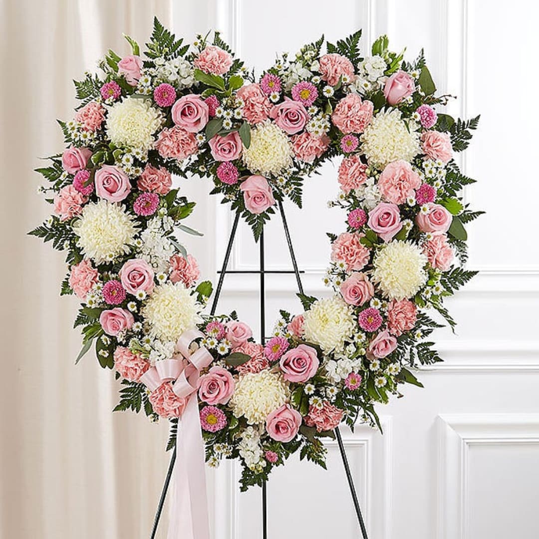 Heart-shaped floral wreath with pink and white flowers on a stand