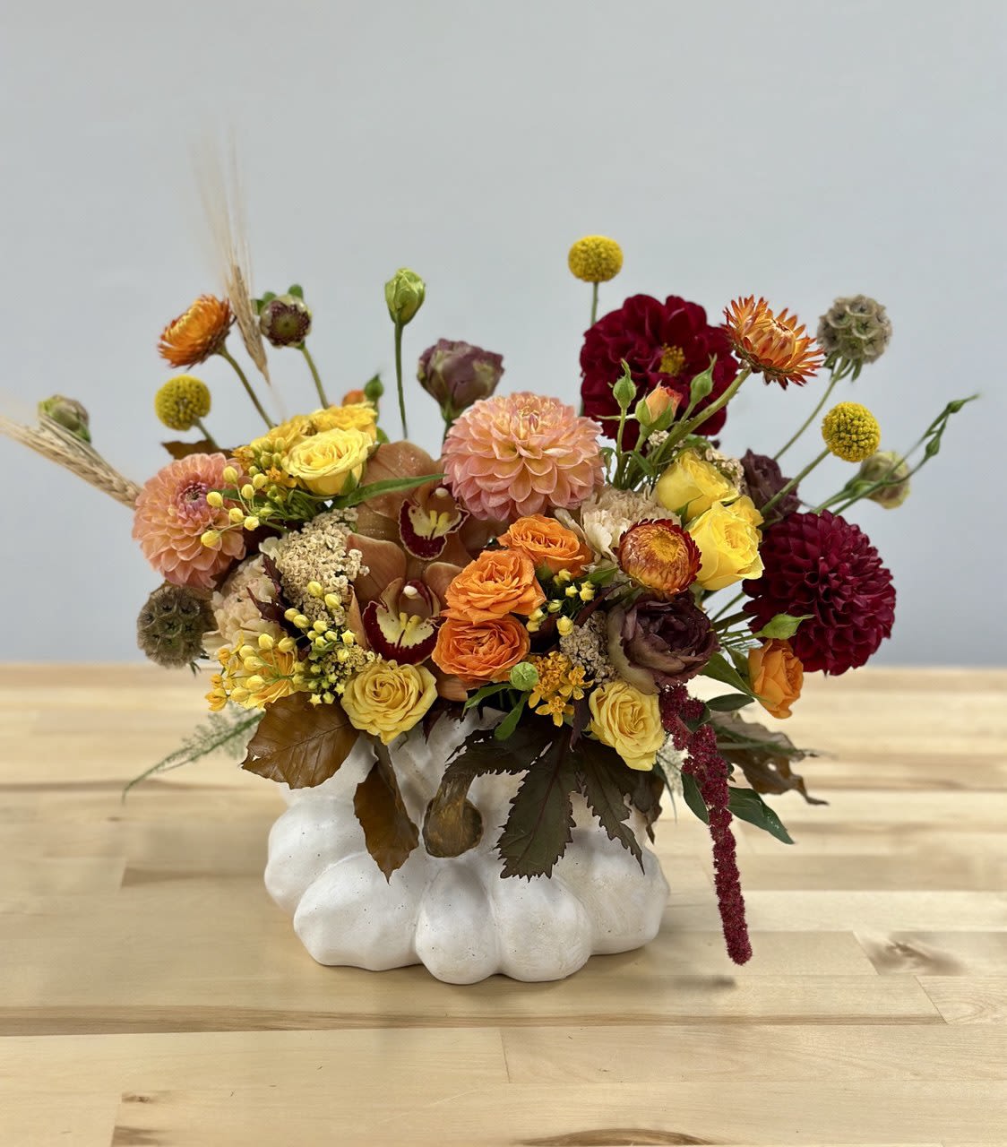 Mixed floral arrangement in a white pumpkin-shaped vase
