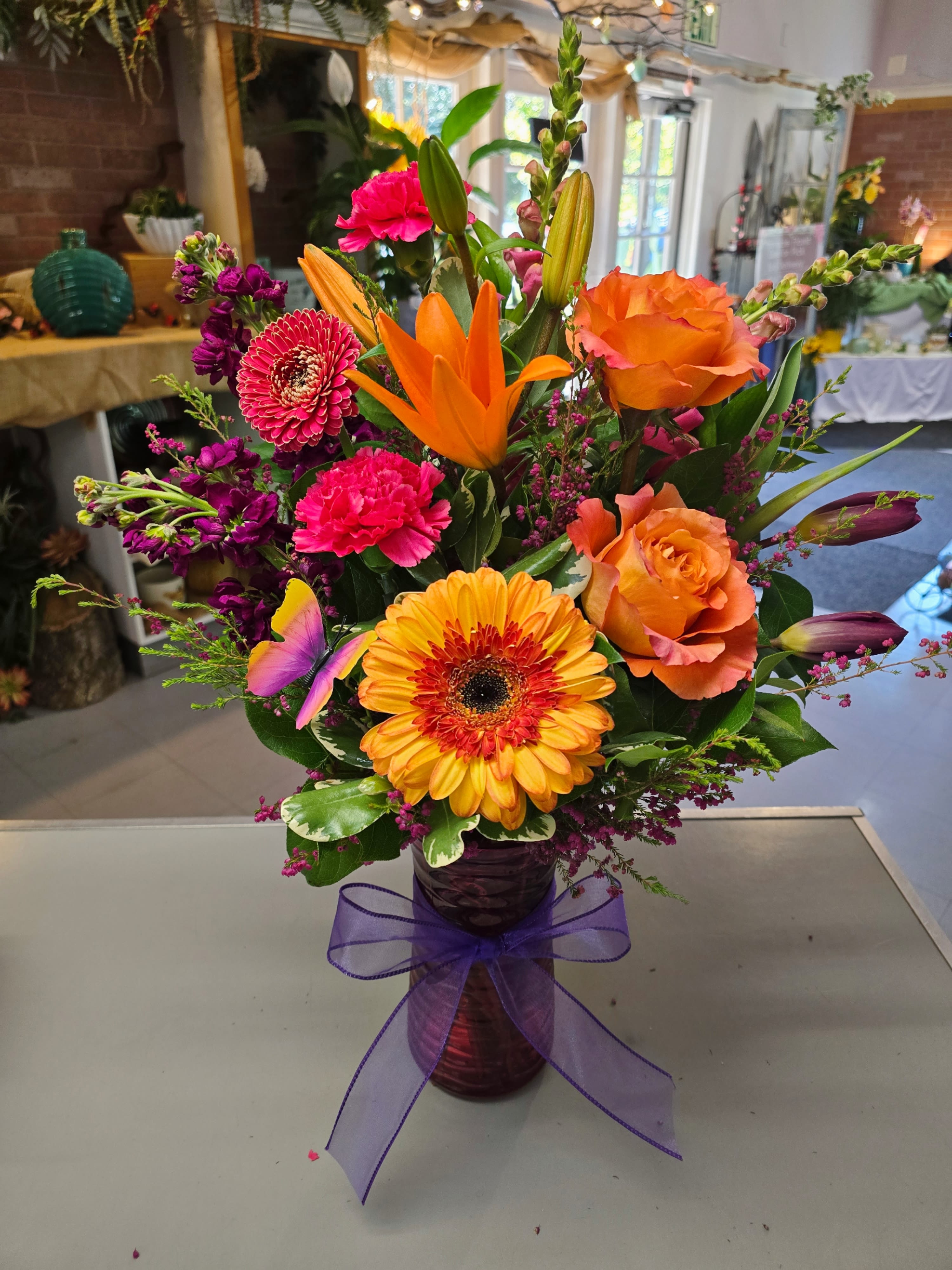 Colorful mixed bouquet in a purple vase with a ribbon