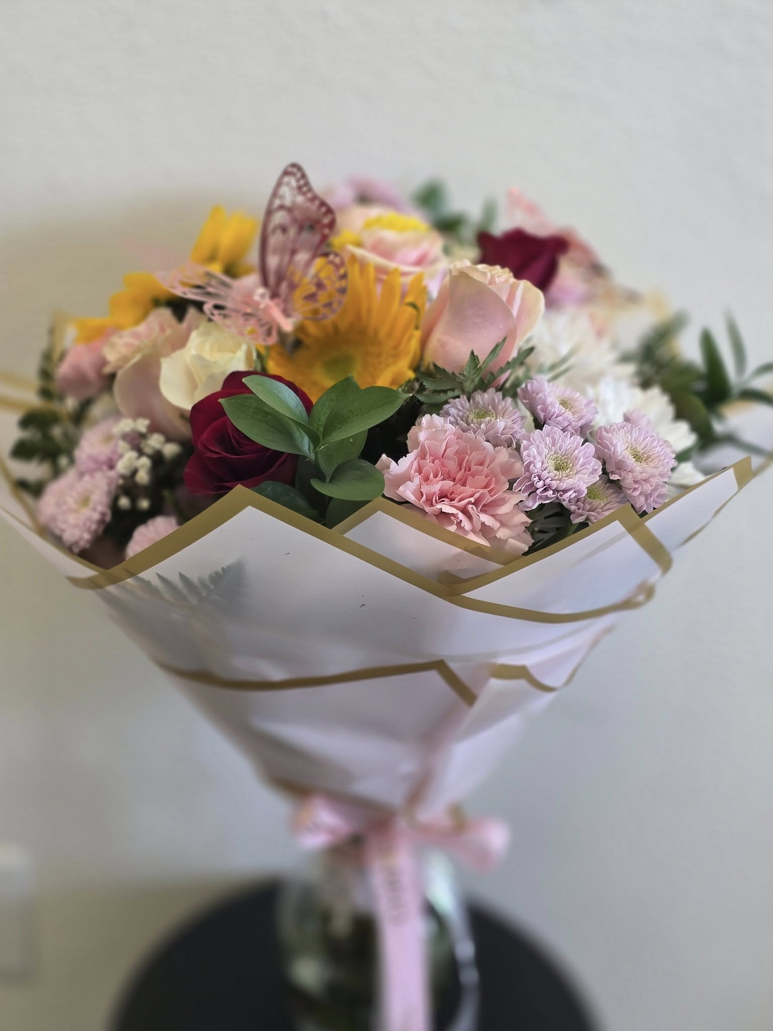 Mixed bouquet of pink, yellow, and white flowers wrapped in white paper