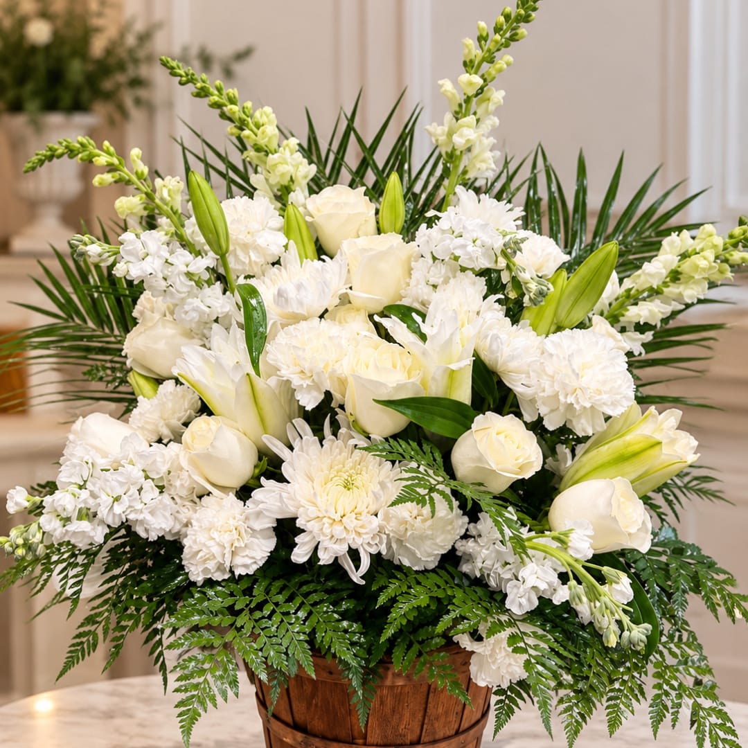 White floral arrangement in a wooden basket with lilies and roses