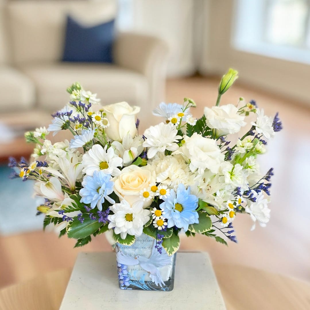 White and blue mixed bouquet in a square glass vase