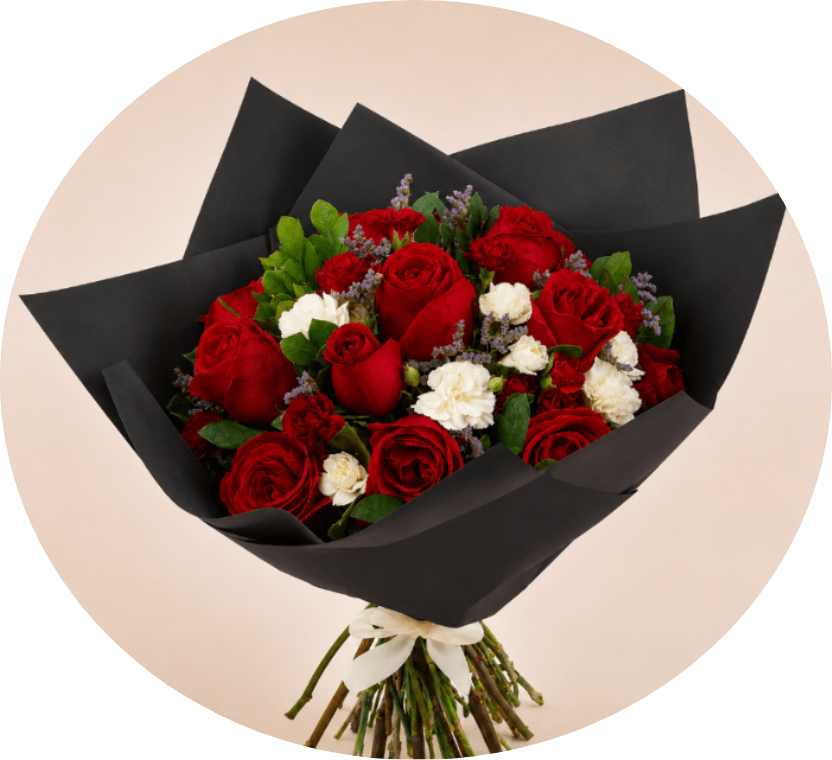Red Rose and White Carnation Bouquet in Black Wrap - A dense cluster of velvety red roses framed by crisp white blooms makes this hand-tied flower arrangement an unforgettable romantic gift for anniversaries, Valentine's Day, or any moment when you want the person you're thinking of to feel deeply cherished. The dramatic matte black paper wrap and contrasting white ribbon give the bouquet a formal, polished look that reads both bold and elegant-perfect for a love-themed surprise or a thoughtful, elevated everyday bouquet.  The rounded, full composition pairs large red roses with smaller white carnations (and other delicate white filler blooms), punctuated by tiny purple/lavender accent flowers and fresh greenery for subtle texture. Wrapped in large black paper and finished with a white ribbon, the presentation is gift-ready and striking from every angle. Care: keep stems in fresh water and trim ends before placing in a vase to help the roses and carnations last longer.