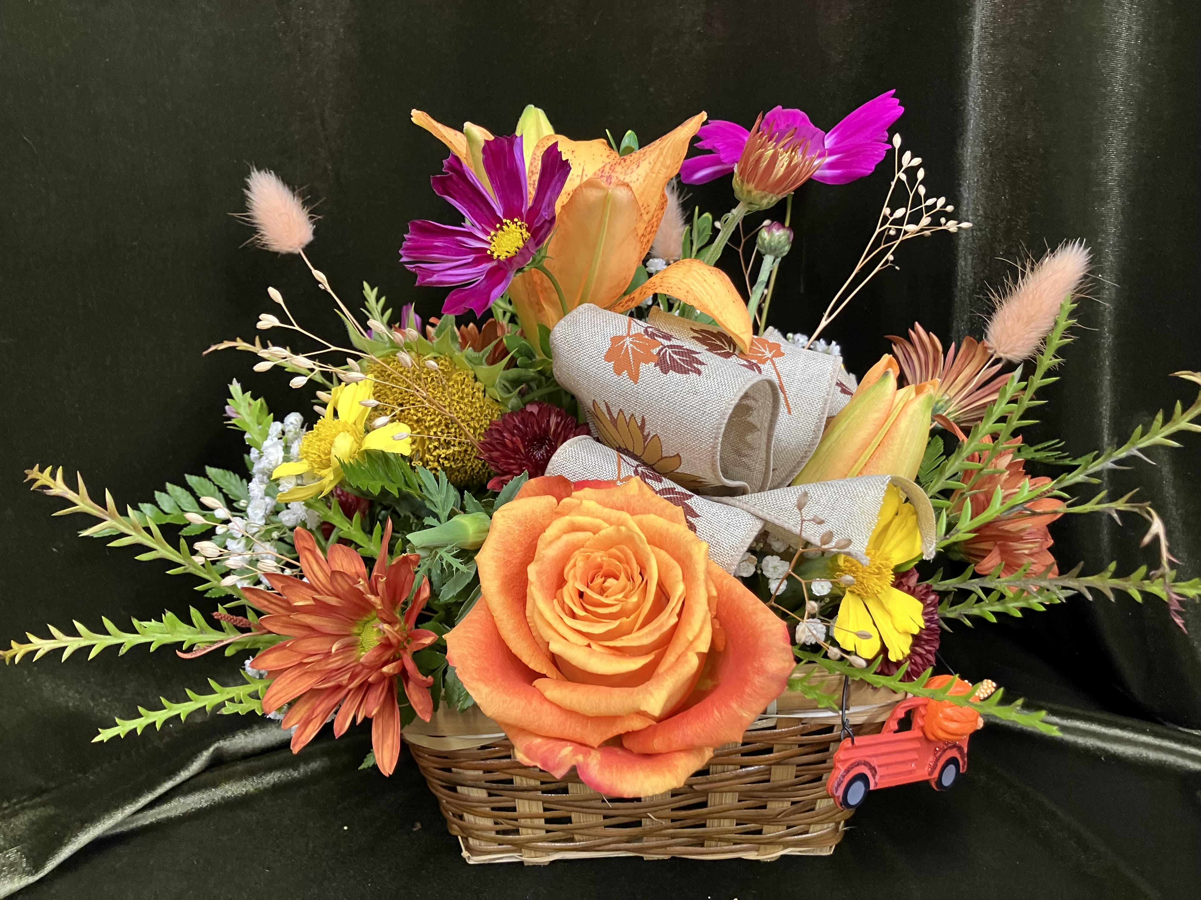 Basket arrangement with orange roses, lilies, and mixed fall flowers