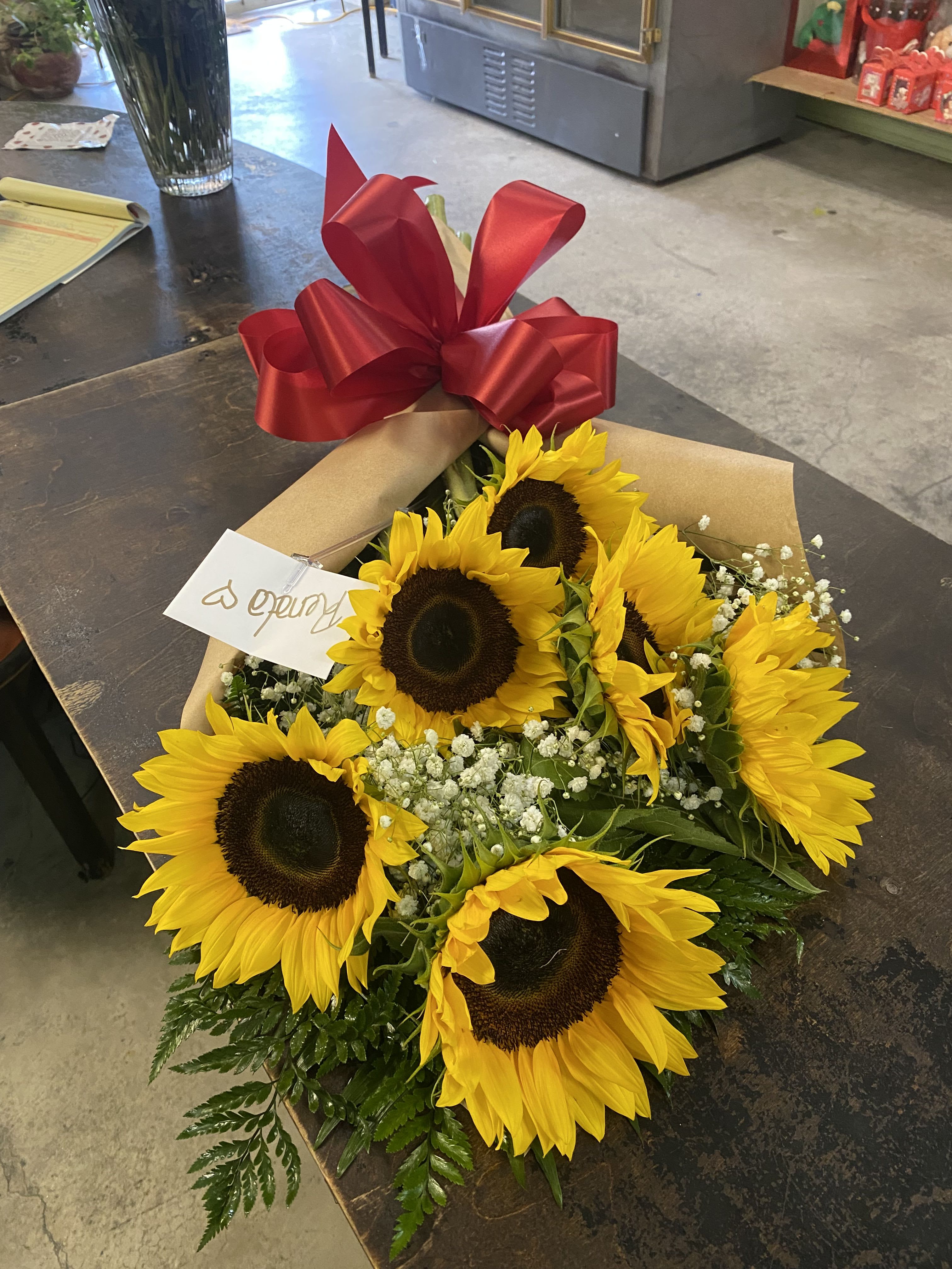 Bouquet of sunflowers wrapped in brown paper with a red ribbon bow