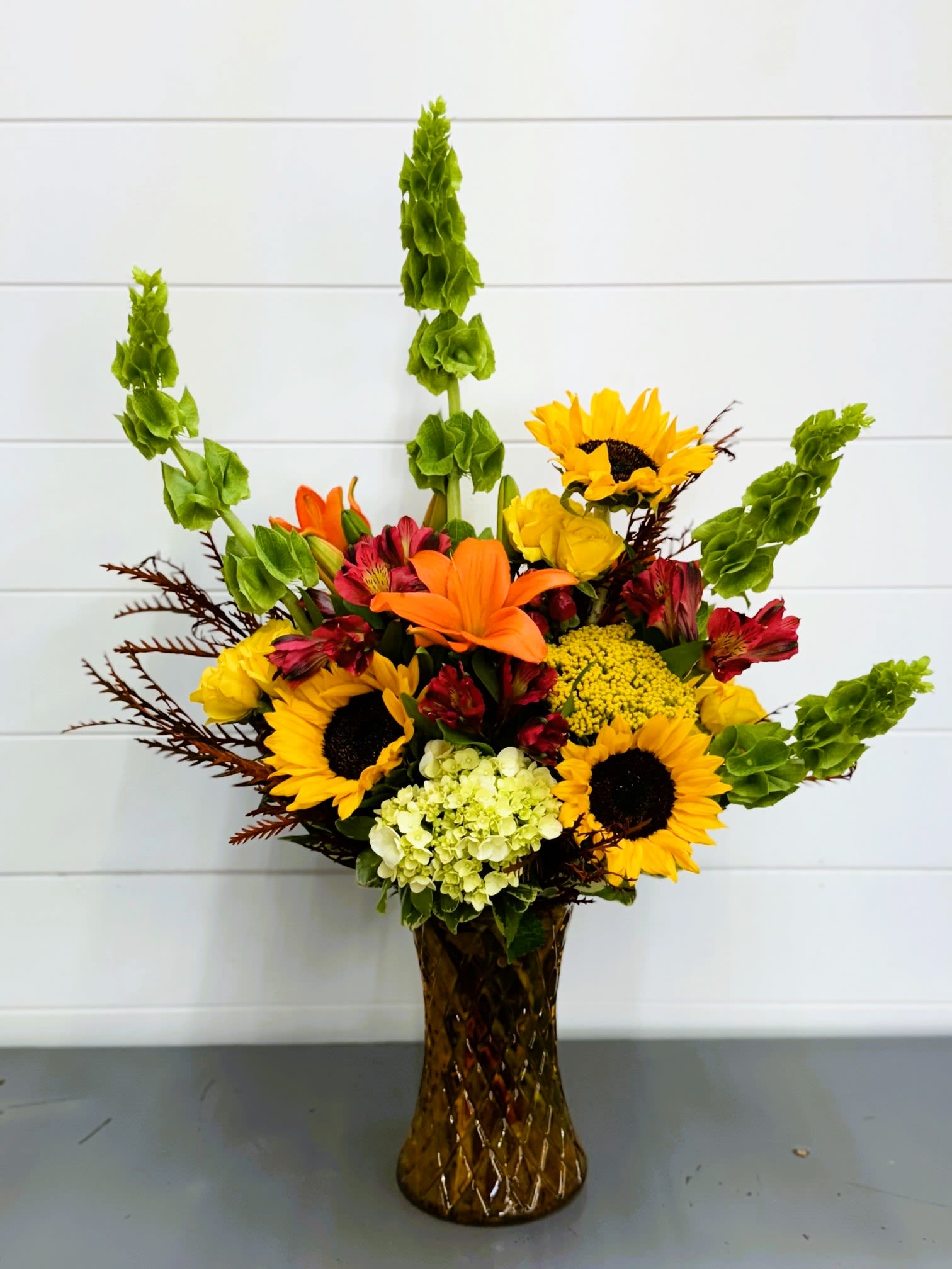Mixed bouquet with sunflowers, lilies, and alstroemeria in a brown vase
