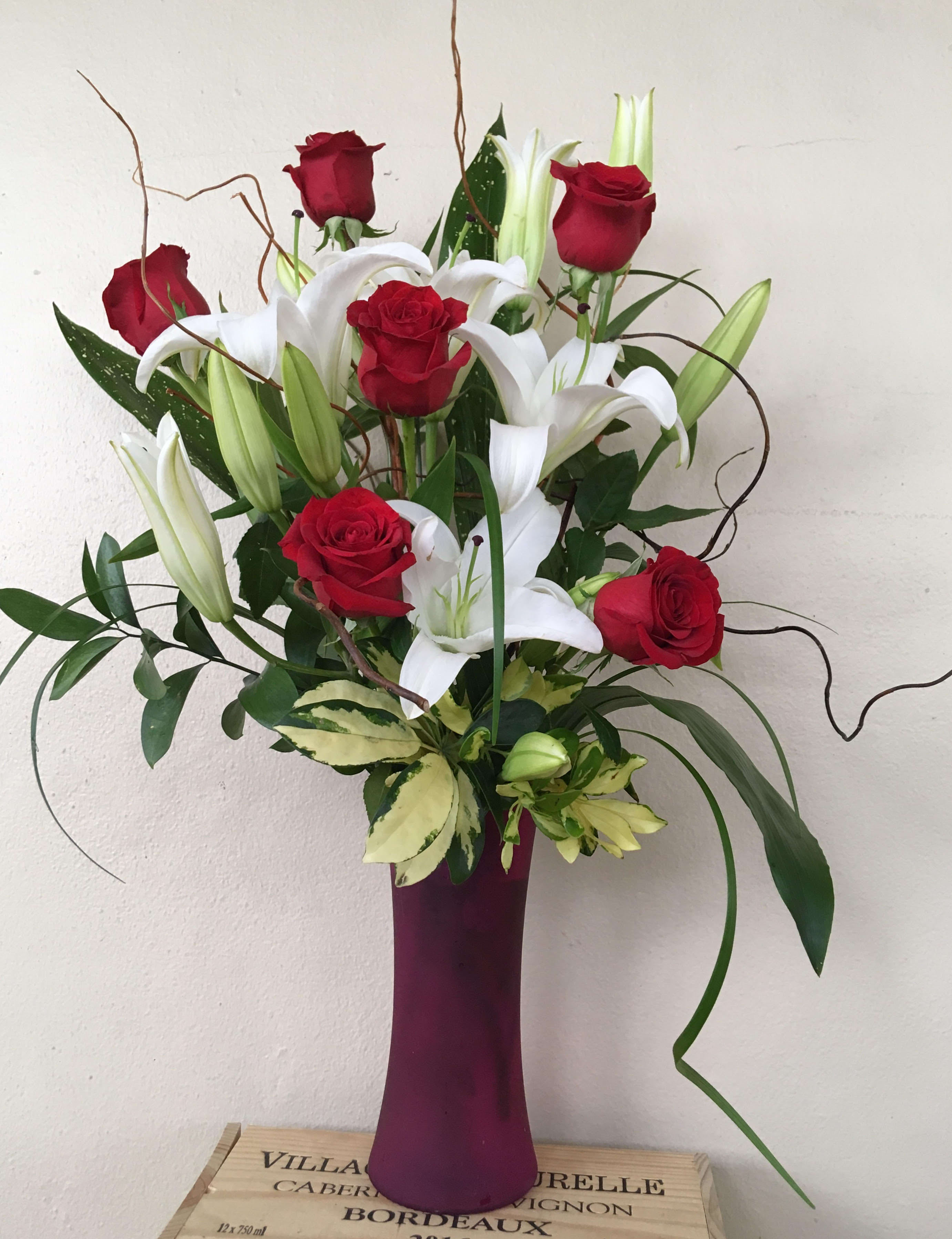 Red roses and white lilies in a tall purple vase