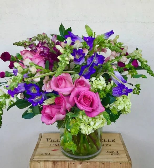Pink roses and purple flowers arranged in a glass vase