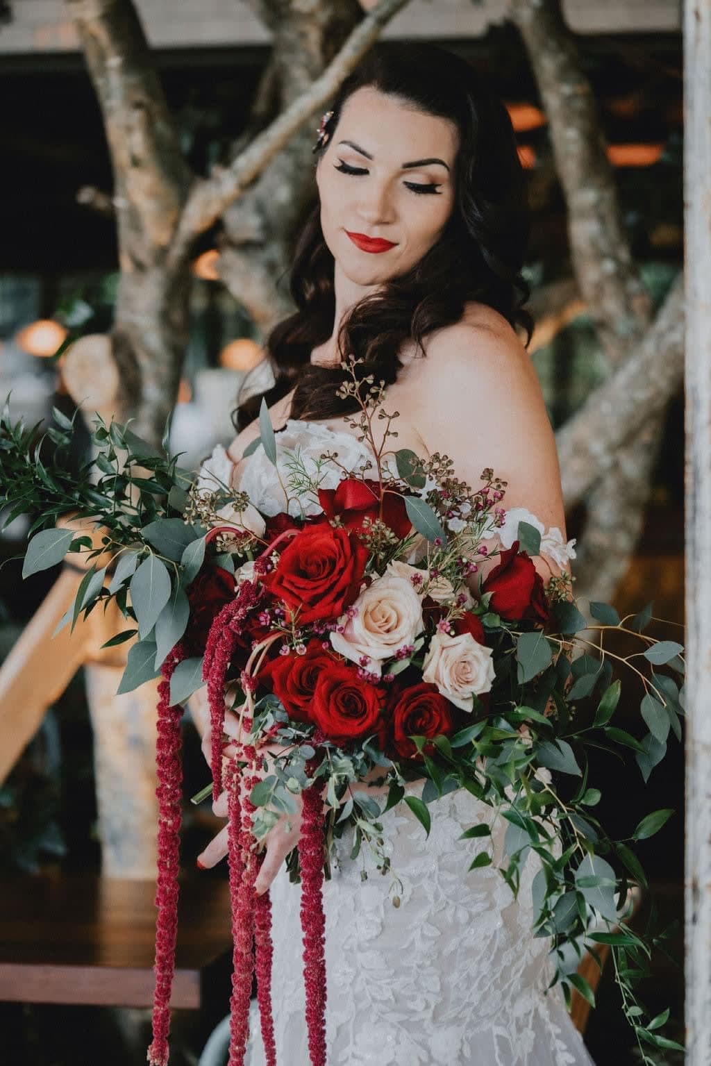 Bride holding a cascading bouquet of red and white roses