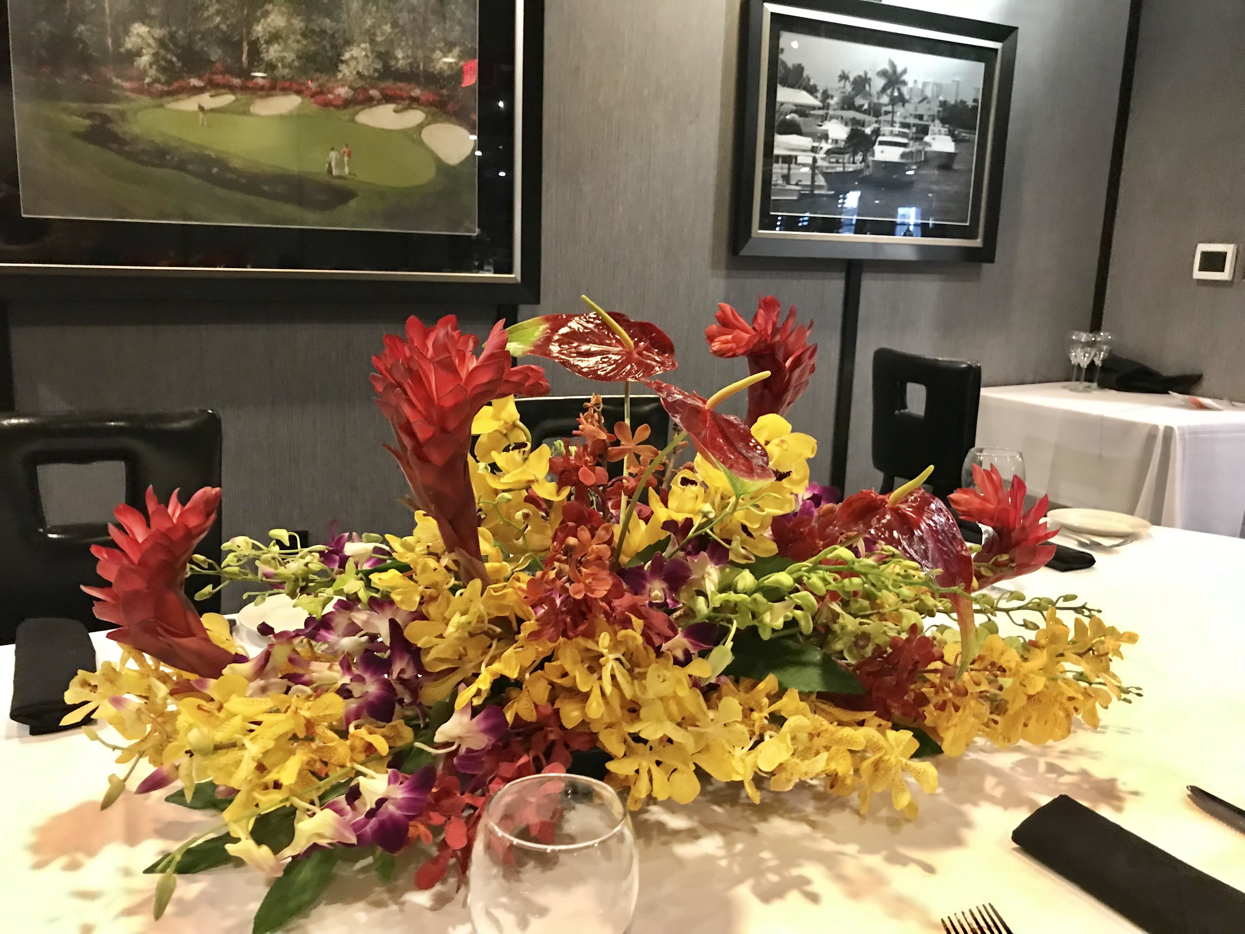 Low tropical centerpiece with red and yellow orchids on a table