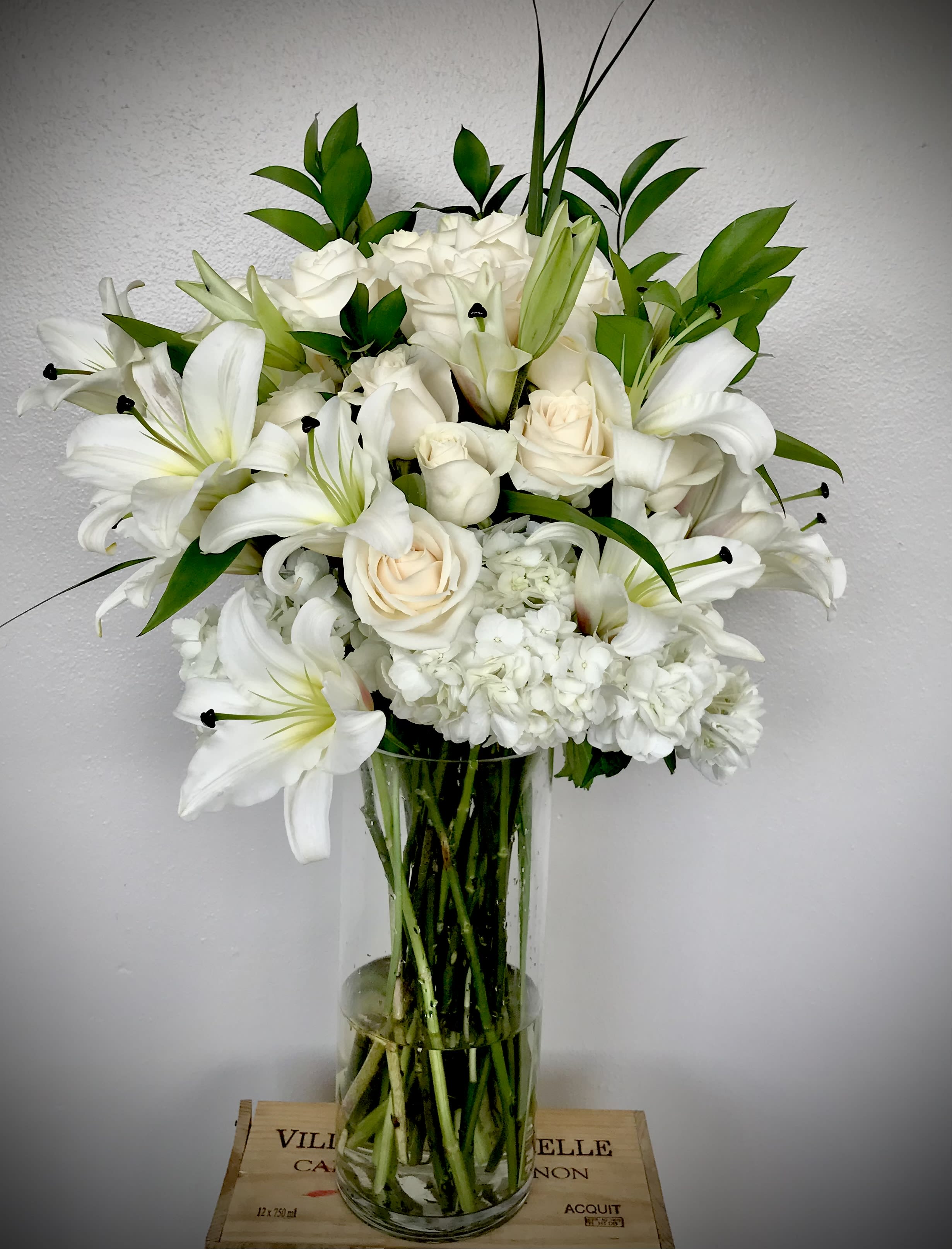 White lilies and roses arranged in a clear glass vase