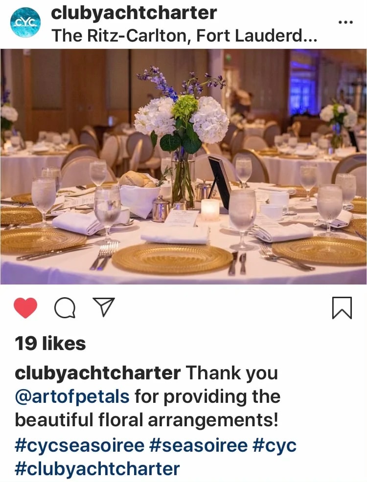 Round banquet table with a white floral centerpiece and gold chargers