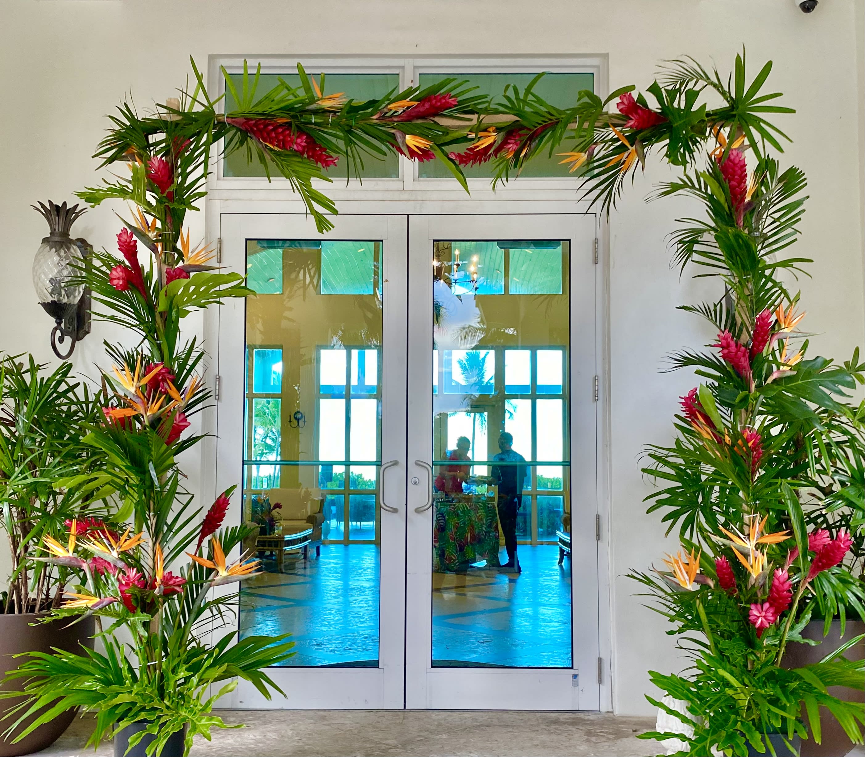 Tropical floral arch with pink and orange flowers framing double doors