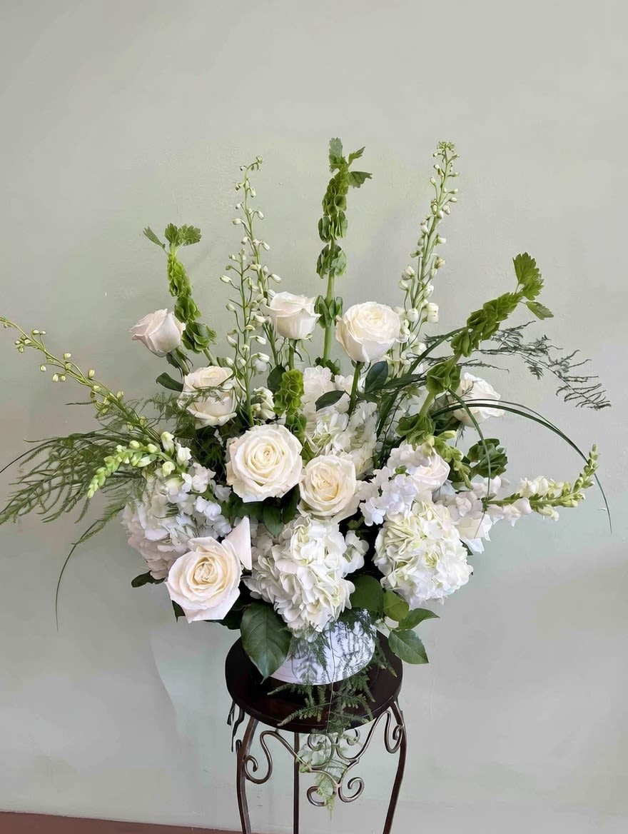 White roses and hydrangeas in a vase with tall green accents