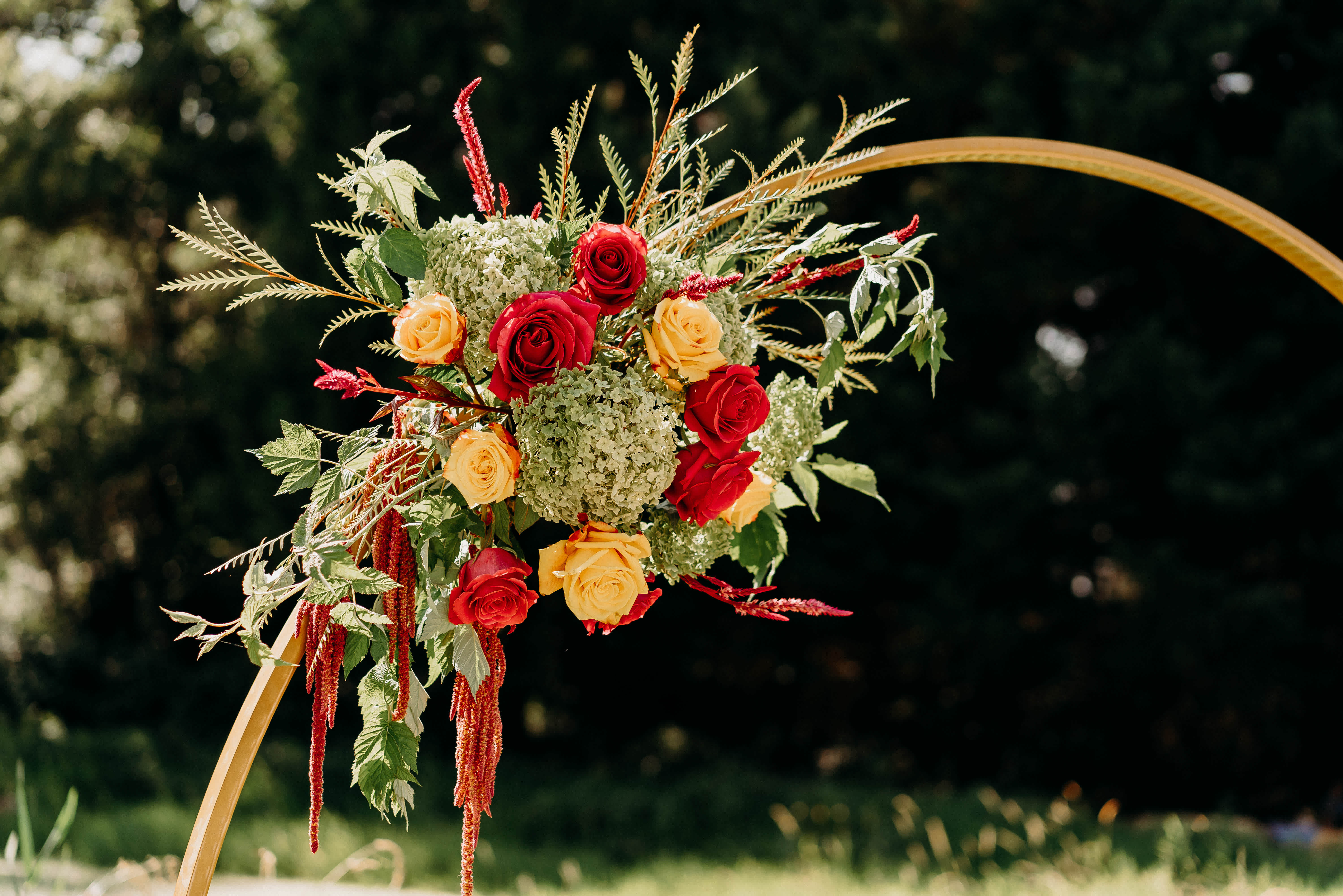Red and yellow roses arranged with greenery on a gold arch