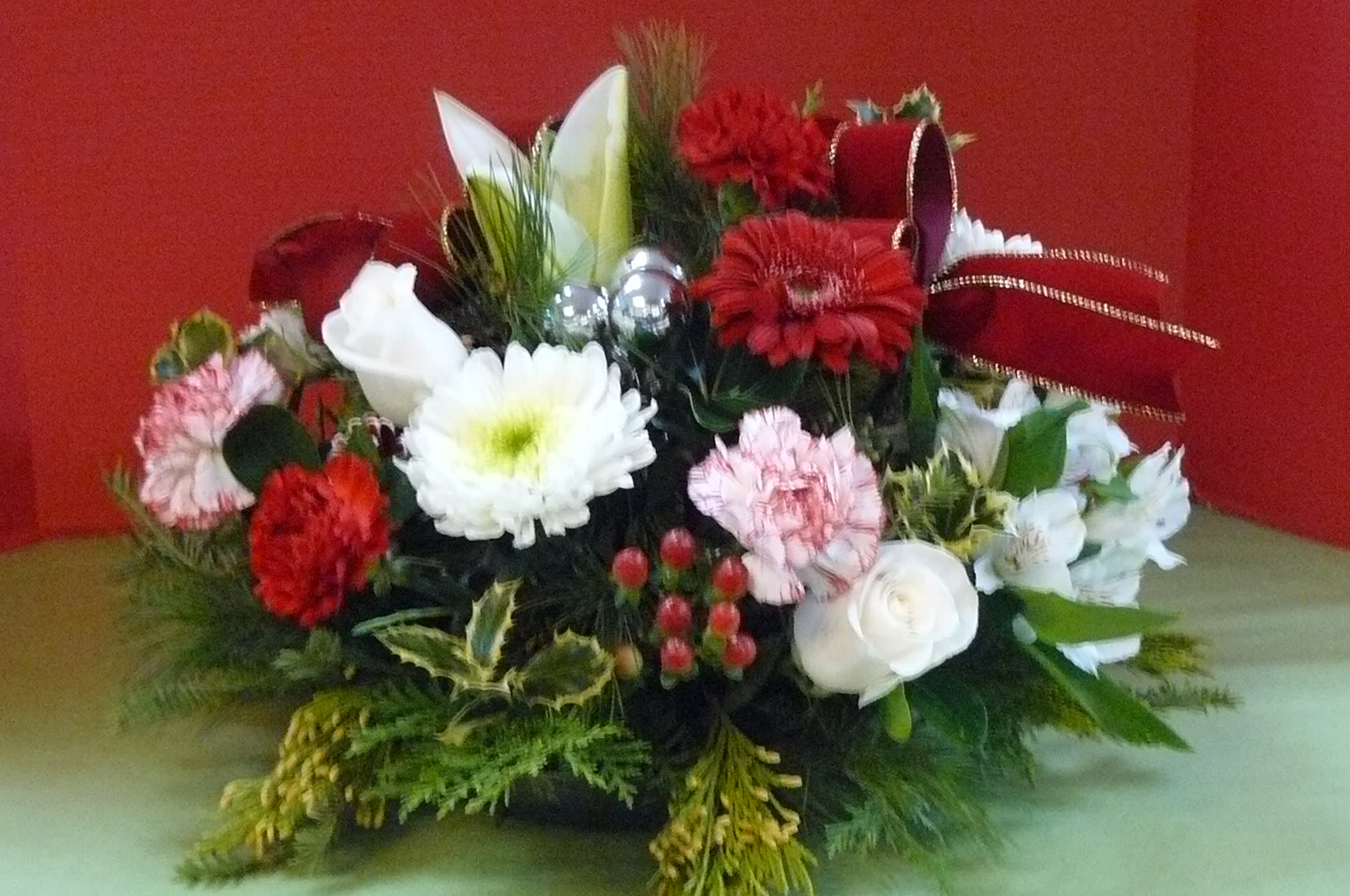 Red, white, and pink floral arrangement with ribbon accents