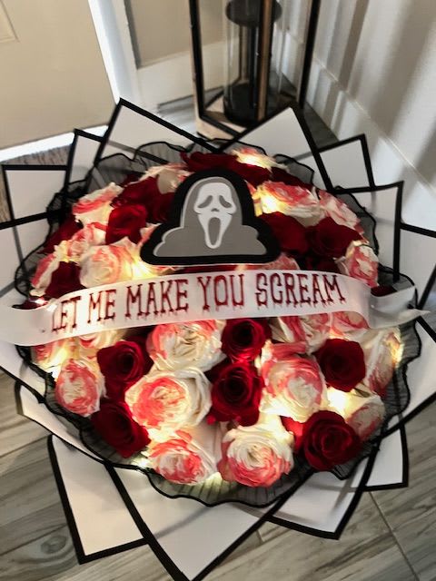 Bouquet of red and white roses with a "Let Me Make You Scream" ribbon