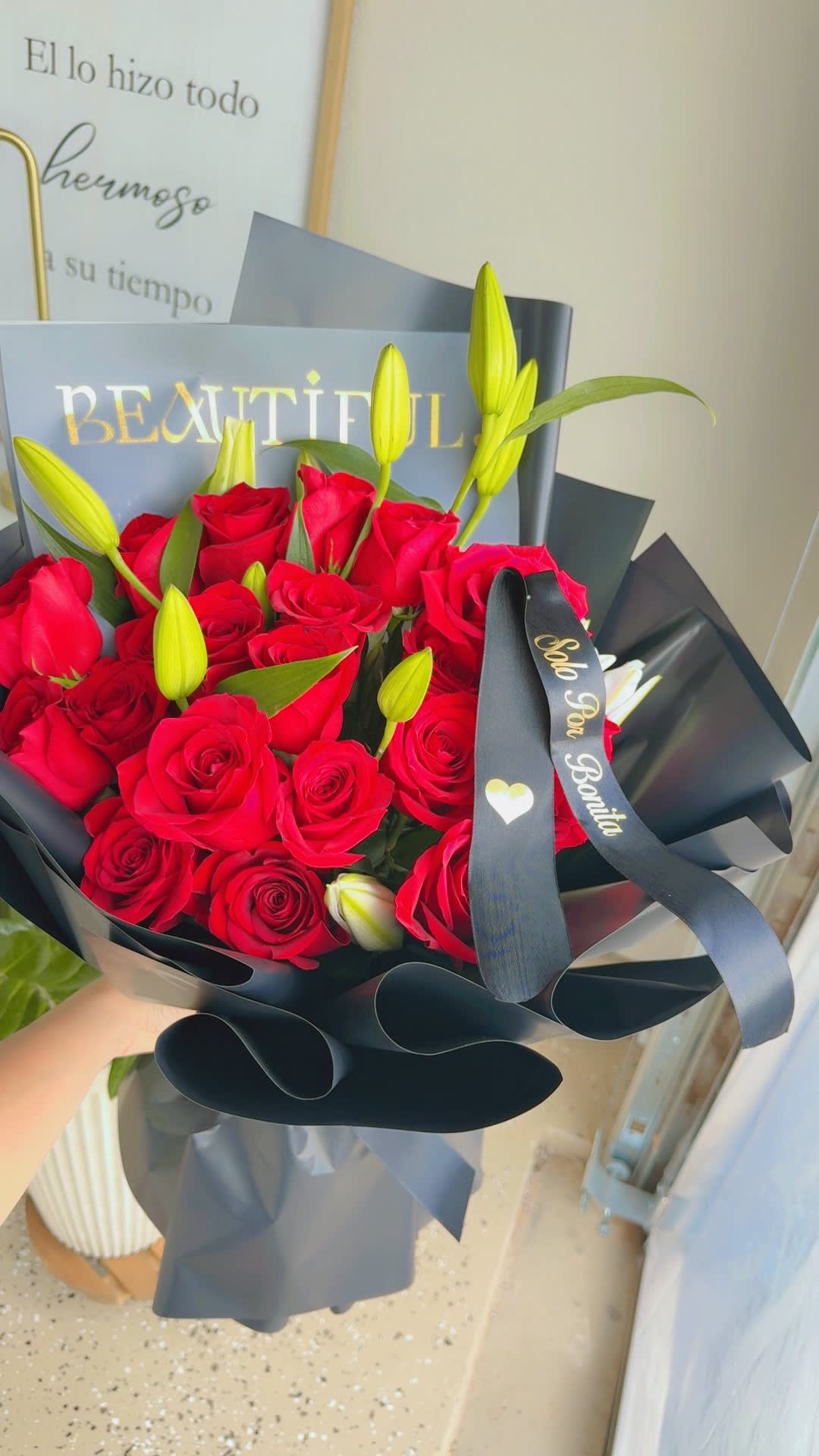 Bouquet of red roses and yellow lily buds wrapped in black paper