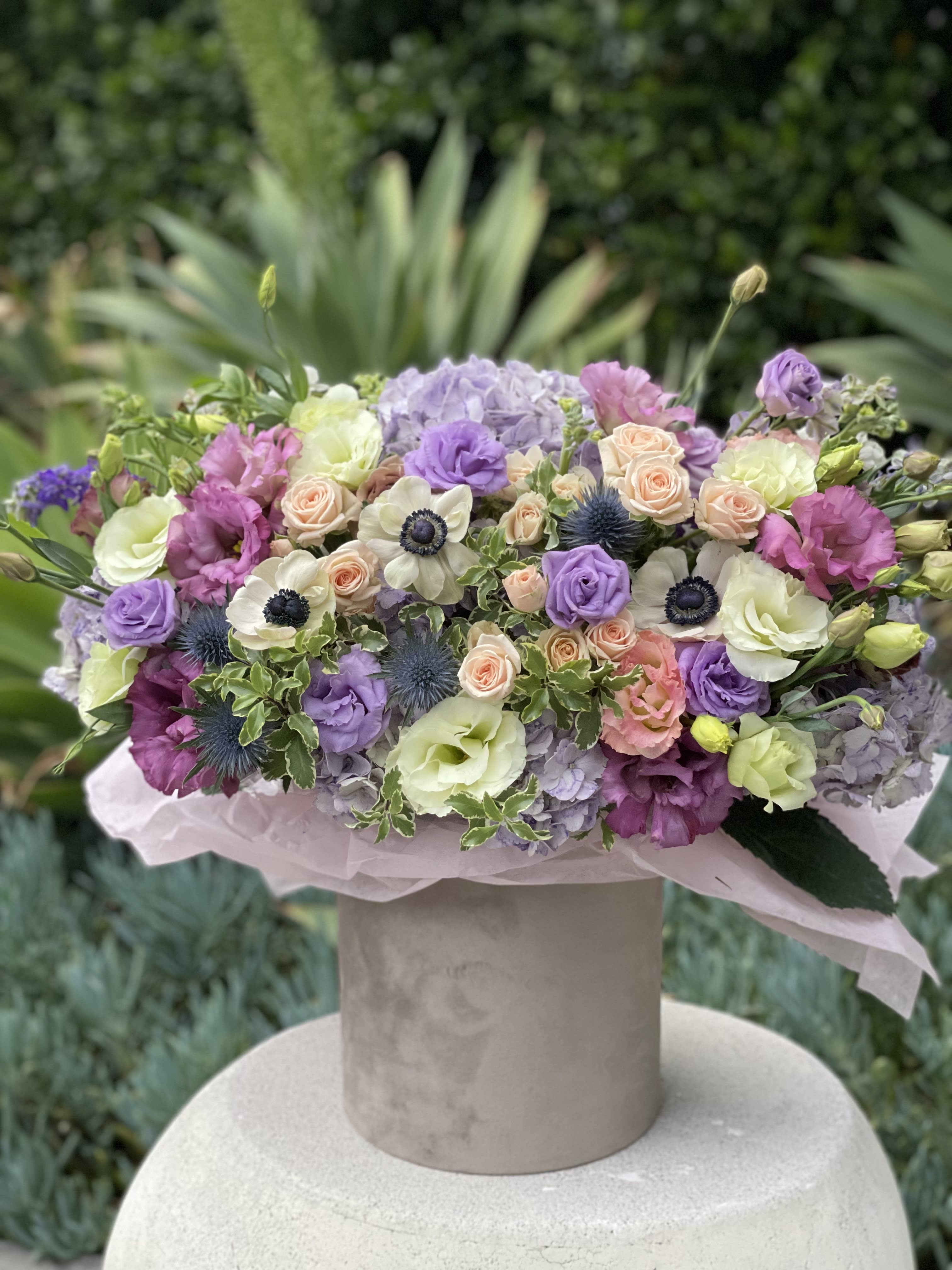 Pastel bouquet of roses, lisianthus, hydrangeas, and anemones in a hatbox