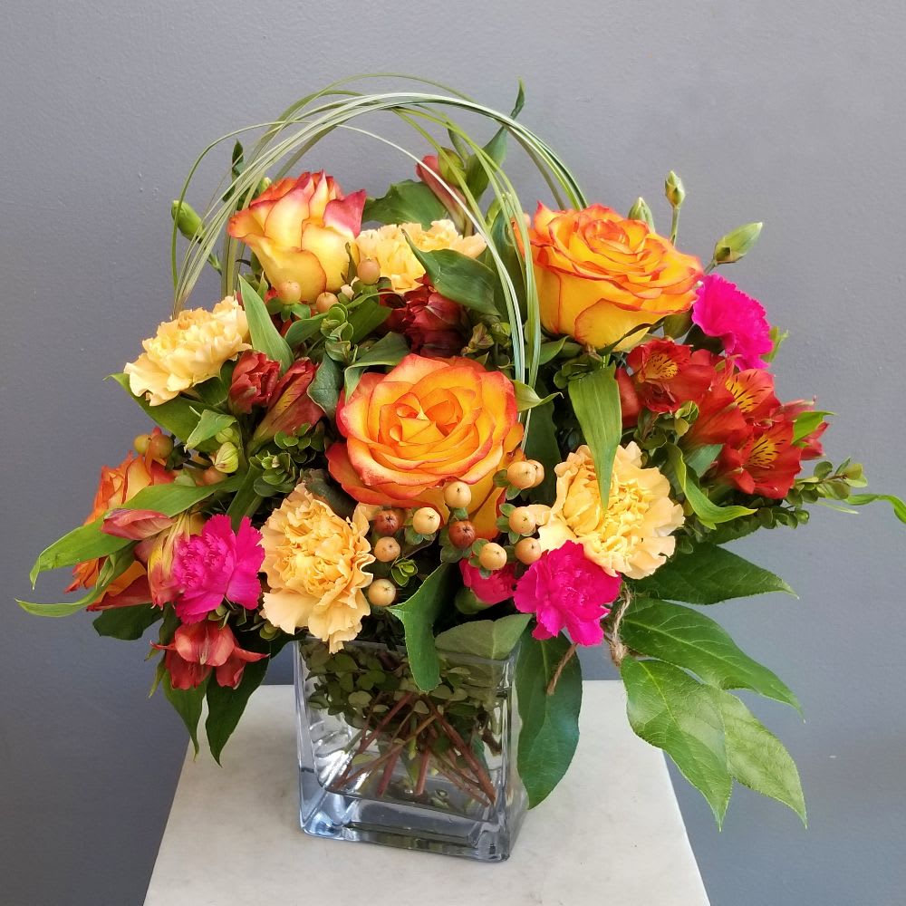 High Magic - High Magic, bright roses and beautiful blooms in a modern square vase. Fits well on a desk or end table. Send a little High Magic today! Another exclusive arrangement from Long Beach favorite five 5 star flower shop, with same day flower delivery A Beautiful California Florist.  Approximate size: 12" Tall x 12" Width