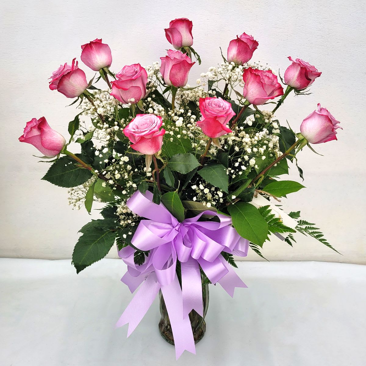 Premium Lavender Roses - One Dozen Lavender Roses with Babies Breath and Bow - Show how much you care with a dozen lux Lavender roses, artfully arranged in a vase with fresh greenery. Soft white baby's breath adds a touch of elegance, while a beautiful lavender bow ties it all together. Perfect for birthdays, anniversary, or any day you want to express your love and appreciation.