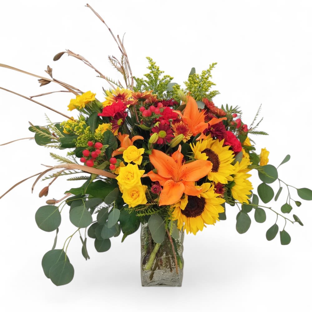 Autumn Serenade - Bring the sweet music of fall into your home with our stunning Autumn Serenade arrangement. This exquisite floral bouquet is a true masterpiece, filled with the rich, vibrant colors of autumn. Our expert florists artfully combine a symphony of fresh flowers, including bold sunflowers, orange lilies, yellow roses, mums, and hypericum berries.  The arrangement is gracefully accented with cascading eucalyptus and dried floral elements, adding beautiful texture and a rustic, natural feel. This autumn arrangement captures the warmth and richness of the season, making it a perfect fall centerpiece for your dining room table or a thoughtful gift for any occasion.  As the fall season evolves, so do our blooms. Please note that while the overall design and vibrant color palette will be maintained, some flowers may be substituted based on daily availability to ensure the highest quality and freshness.  Order your Autumn Serenade today from A Beautiful California Florist, Long Beach's premier flower shop, offering same-day flower delivery to brighten any space with a touch of fall magic.     • Approximate size: 22" T x 22" W     • Floral varieties include: Sunflowers, Lilies, Roses, Mums, Hypericum Berries, Eucalyptus, and dried elements.     • Perfect for: Fall Decor, Thanksgiving, Anniversary, Birthday, or any special occasion.