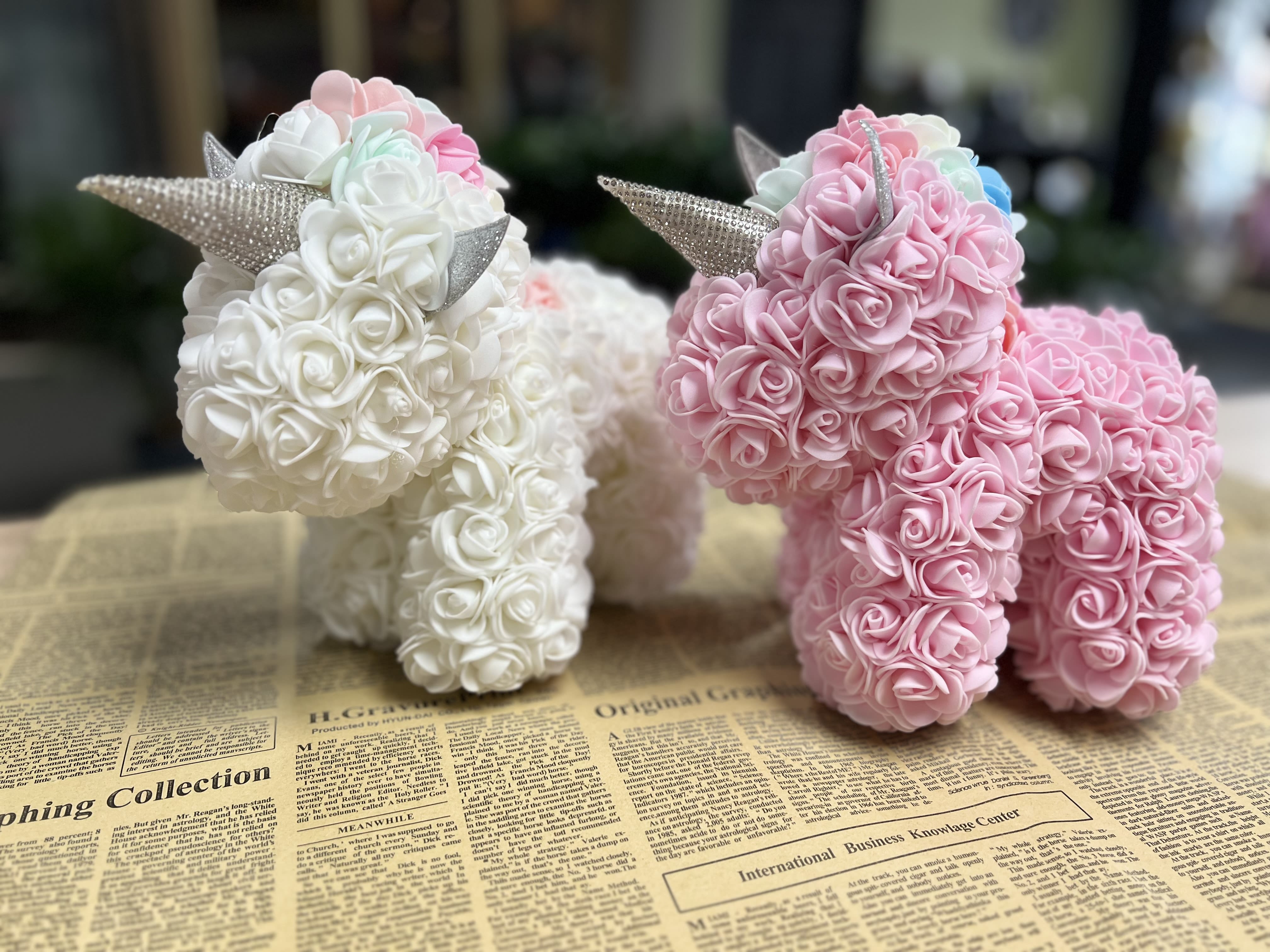 Two small unicorn figurines covered in pink and white roses