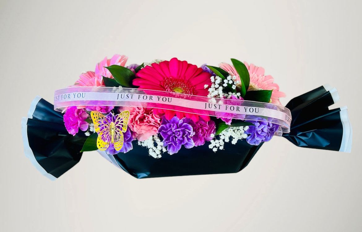 Colorful bouquet with gerbera daisies and carnations wrapped in dark paper